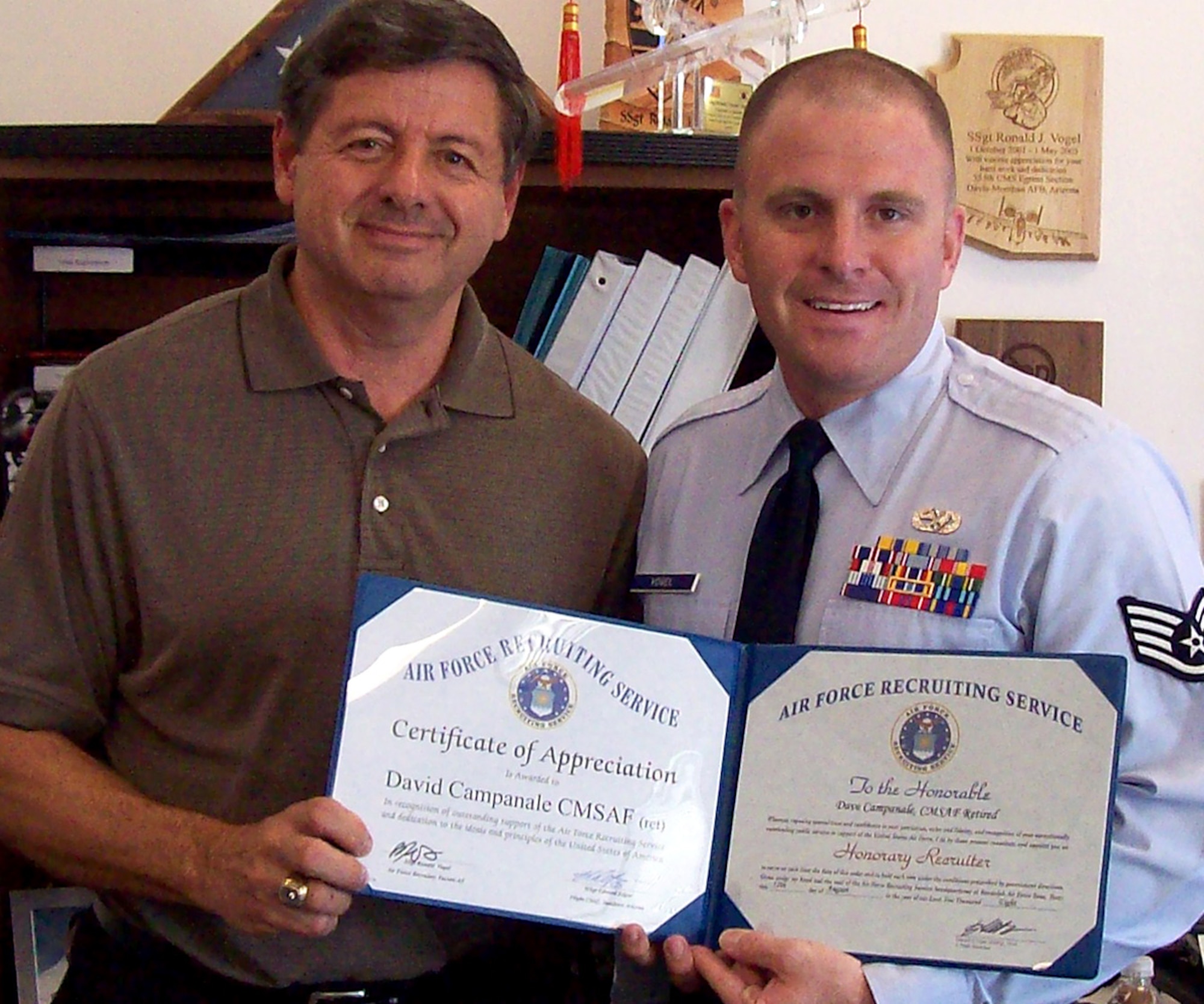 Staff Sgt. Ronald Vogel and retired Chief Master Sgt. David Campanale pause for a photo in the Air Force recruiting office in Tucson, Ariz., Aug. 12. The 362nd Recruiting Squadron recruiter presented the eleventh Chief Master Sergeant of the Air Force a certificate of appreciation for sharing his professional insights and personal experiences with about 40 future Airmen at the Tuscon office Delayed Entry Program Commander’s Call that day. (U.S. Air Force photo)