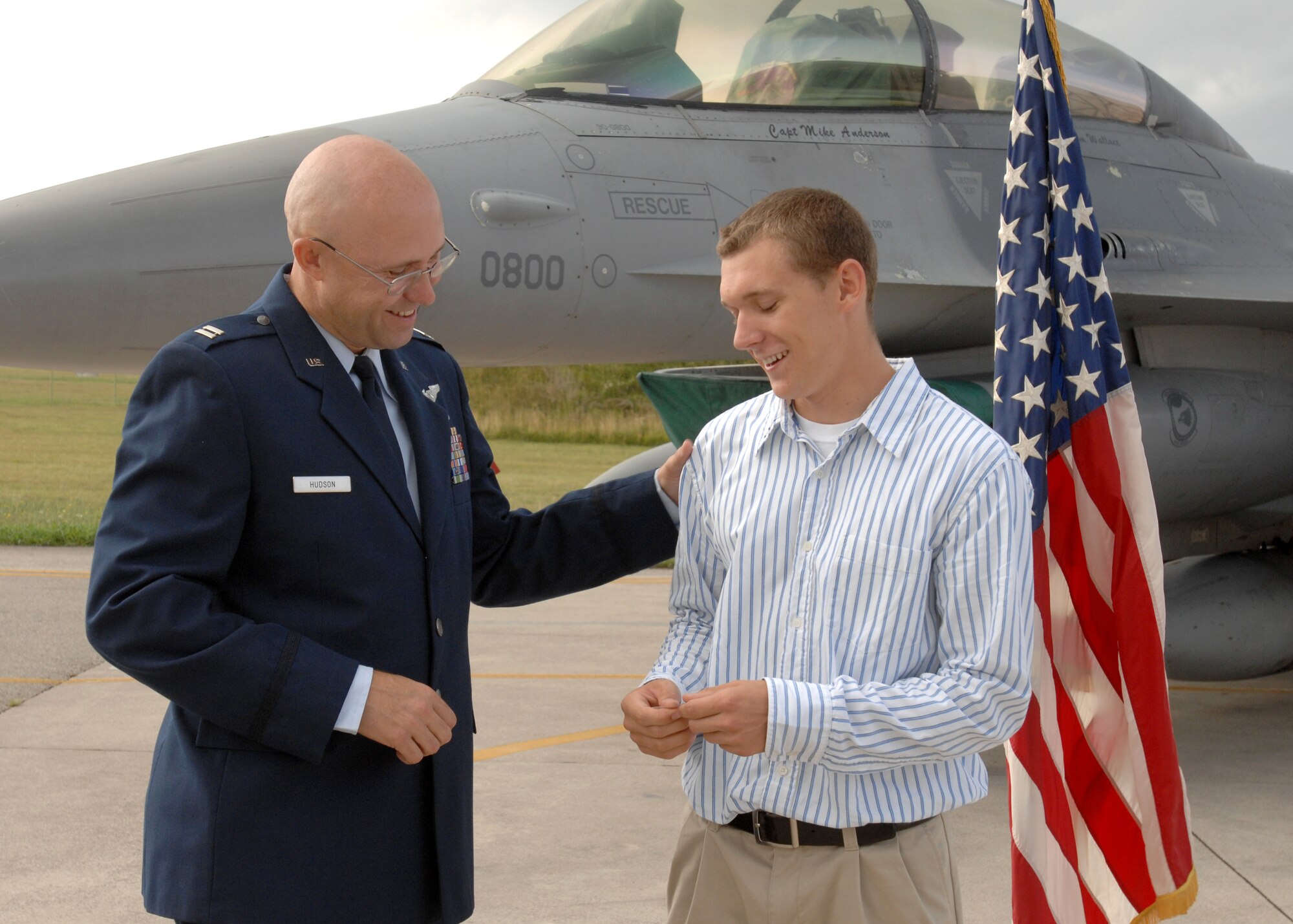 AVIANO AIR BASE, Italy --  Capt. Charles Hudson of the 603rd Air Control Squadron presents his son, Marcus Hudson, with an airman 1st class coin after enlisting him into the Air Force, Aug. 12.  The coin represents the rank that Marcus will put on after completion of basic training.  (U.S. Air Force photo/Airman 1st Class Tabitha M. Mans)