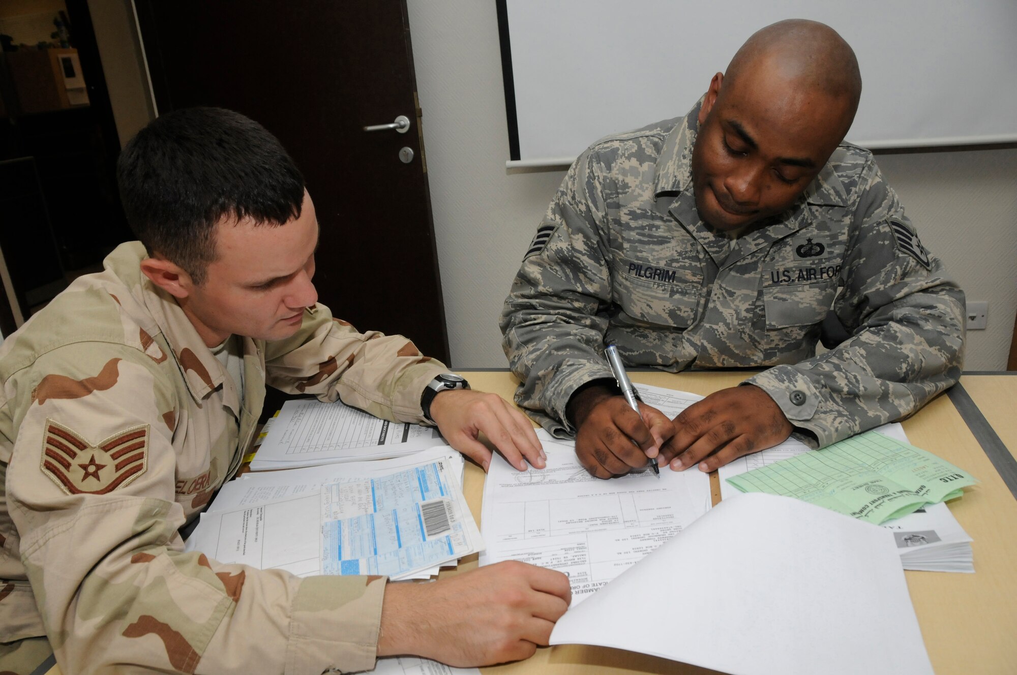 Staff Sgt. Scott DeLoera and Staff Sgt. Toine Pilgrim, both contracting officers with the 379th Expeditionary Contracting Squadron, review customs documents Aug. 18, 2008, at an undisclosed air base in Southwest Asia. Sergeant DeLoera, a native of Washington, D.C., is deployed from Anderson Air Base, Guam, and Sergeant Pilgrim, a native of Queens, N.Y., is deployed from McConnell Air Force Base, Kan., in support of Operations Iraqi Freedom, Enduring Freedom and Joint Task Force-Horn of Africa. (U.S. Air Force photo by Staff Sgt. Darnell T. Cannady/Released)
