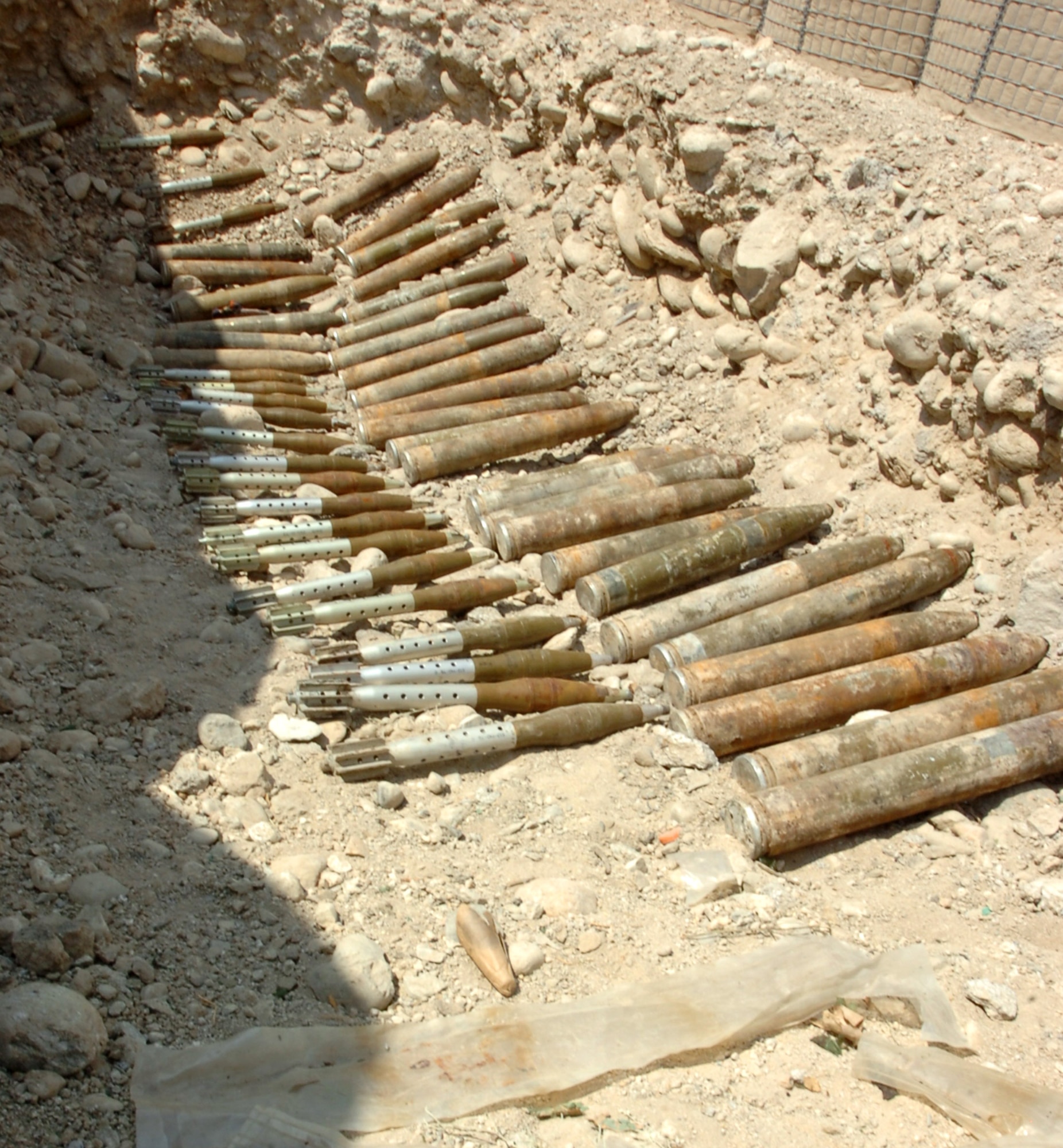 Munitions to include 31 107mm rockets and 20 RPGs are lined up in a pit at Forward Operating Base Methar Lam, Aug. 3. The munitions are a part of a weapons cache that a member of the Law Enforcement Professional's surveillance team turned in to the Small Rewards Program. (U.S. Army photo/ Sgt. Jessica R. Dahlberg)