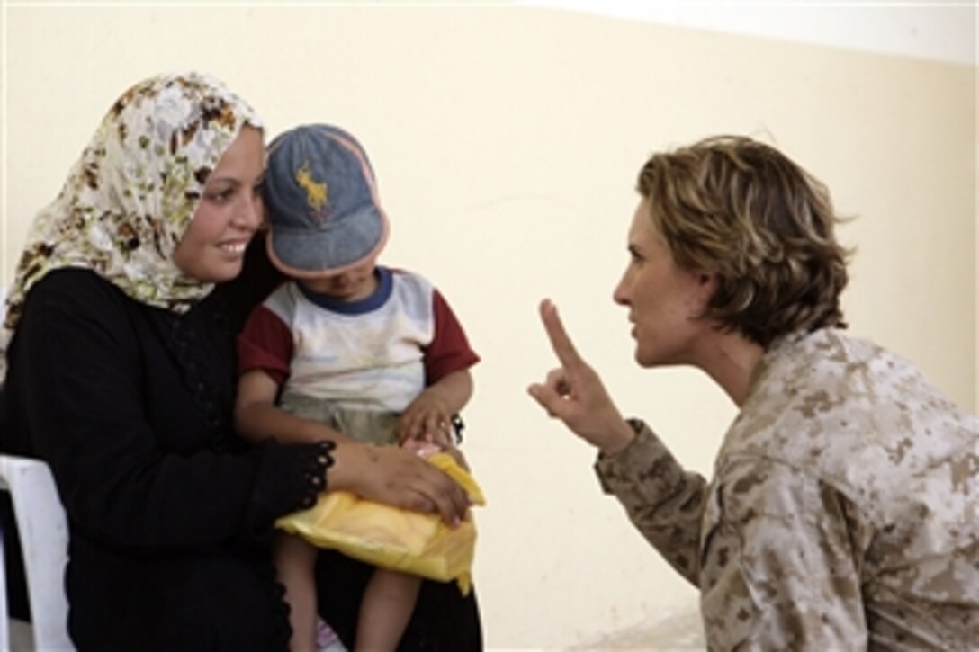 U.S. Marine Corps Gunnery Sgt. Cutledge, from Regimental Combat Team 1, speaks with an Iraqi mother and her daughter during a cooperative medical engagement in Karmah, Iraq, on Aug. 12, 2008.  Iraqi police officers and Marines with Civil Affairs Detachment, 2nd Battalion, 11th Marine Regiment, Combat Logistics Battalion 1 and elements of I Marine Expeditionary Force are providing health care and food to residents.  