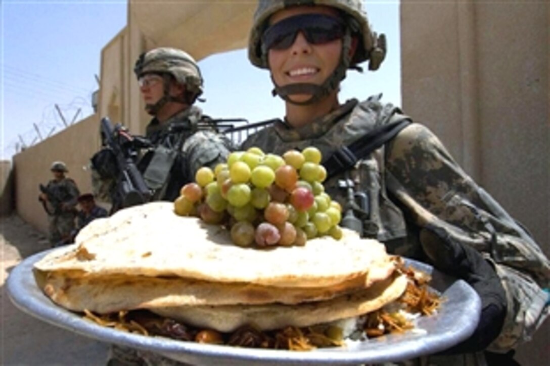 U.S. Army Sgt. Alyson Brown displays a platter of food provided to U.S. soldiers at the end of government-led meetings in Wajihiyah, Iraq, Aug. 16, 2008. The soldiers are assigned to Battery A, 2nd Stryker Cavalry Regiment. 
