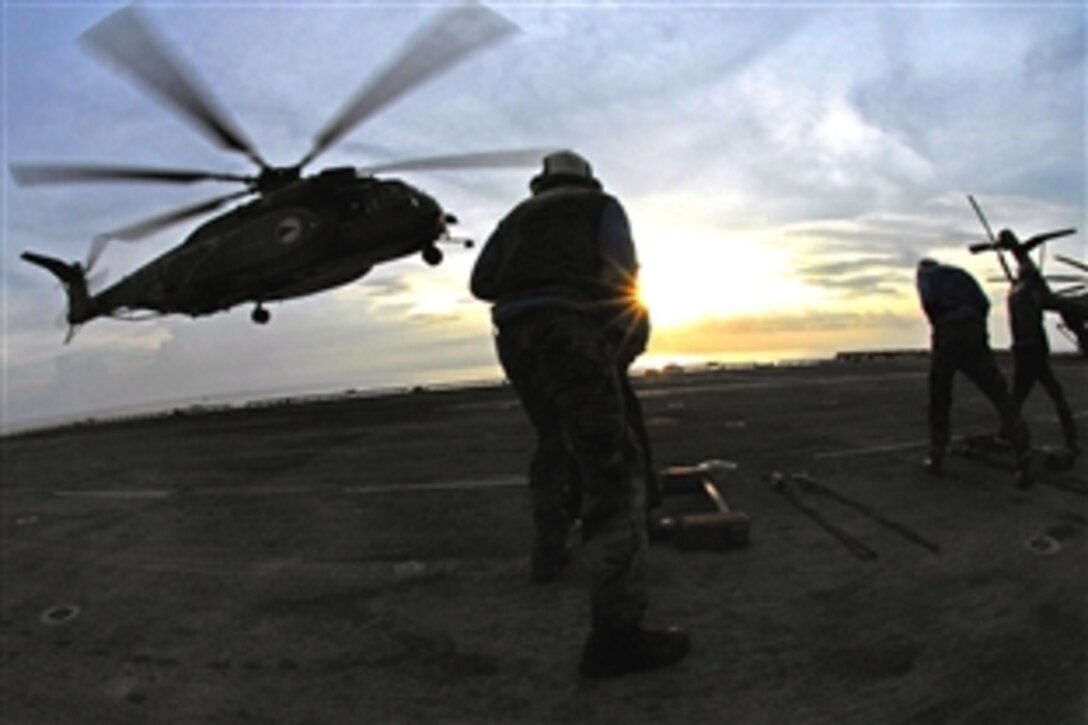 U.S. Navy sailors steady themselves against the downdraft from the rotor blades of a Sea Dragon helicopter aboard the amphibious assault ship USS Tarawa in the Pacific Ocean, Aug. 15, 2008. 