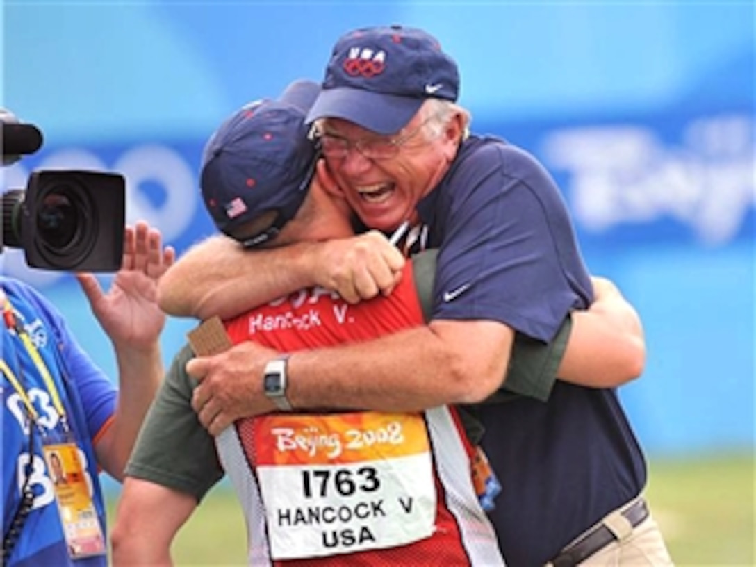 Team USA shotgun coach Lloyd Woodhouse, a retired U.S. Air Force chief master sergeant, hugs U.S. Army Pfc. Vincent Hancock, after the soldier won the Olympic gold medal in men's skeet competiton at the Beijing Shooting Range, Aug. 16, 2008. Hancock is assigned to the U.S. Army Marksmanship Unit on Fort Benning, Ga.
