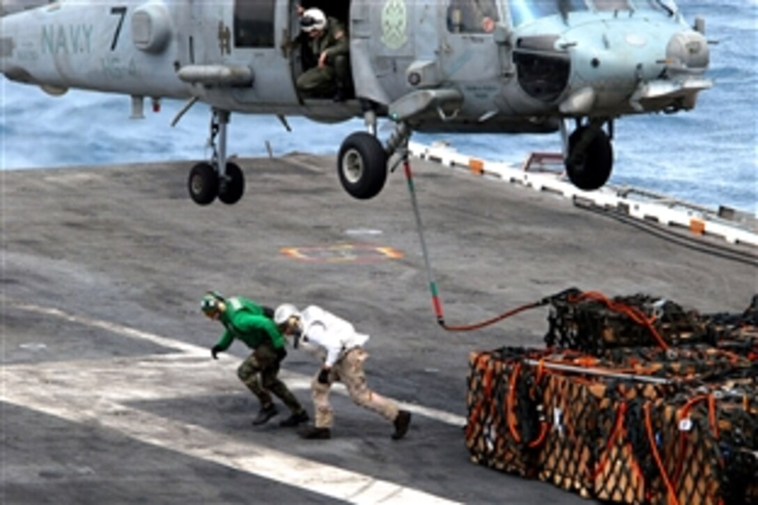 A U.S. Navy sailor checks deck height from the door of a Sea Hawk helicopter while sailors aboard the aircraft carrier USS Ronald Reagan sprint to clear the rotor wash after attaching a sling-load in the Pacific Ocean, Aug. 15, 2008. 