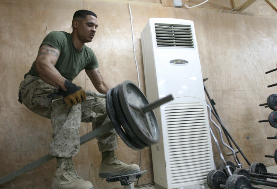 Sgt. Damien Robinson, administrative chief and linguist manager with Headquarters and Service Company, Task Force 2nd Battalion, 2nd Marines, Regimental Combat Team 5, completes a bent-over row exercise on equipment made from various scrap parts on Combat Outpost Rawah, Iraq, August 19. Many improvised machines will be replaced by manufactured equipment when the new gym is completed.  The outpost will also have other improvements in the next few months such as new living quarters and a new chow hall that will improving the quality of life for the Marines there.