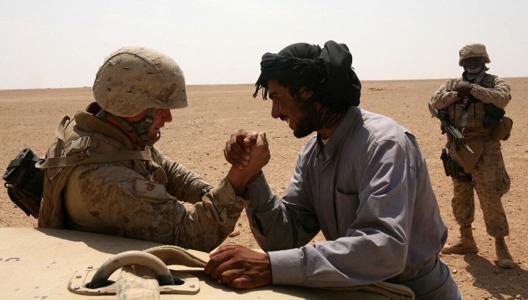 Sgt. Karter Elliott arm wrestles an Iraqi while deployed as a patrol leader with Marine Wing Support Squadron 274. Elliott and his Marines interacted with Iraqis while conducting their security patrols.