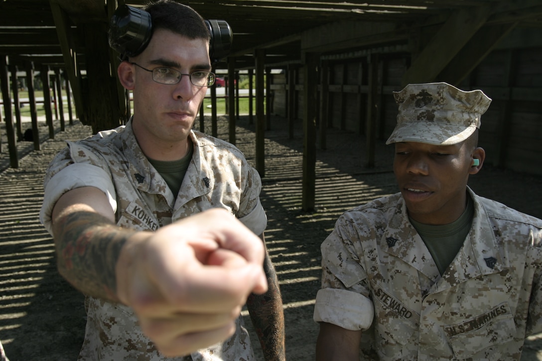 Sgt. Ekhart Kohkemper, , a training noncommissioned officer with Marine Special Operations Support Group, U.S. Marine Corps Forces, Special Operations Command, covers trigger control with MARSOC shooter during annual pistol qualification, Aug 19 at Pistol Range D-30 here. Serving as a range coach is one of Kohkemper’s duties as a training NCO.
