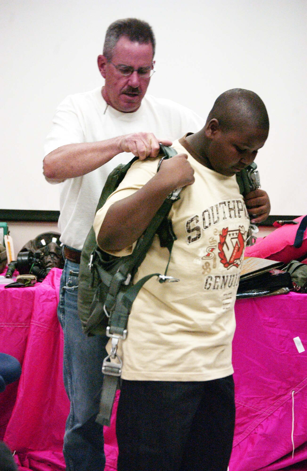 Master Sgt. Dennis Martin, Aircrew Flight Equipment Craftsman, helps Jerry Wilson, 11, don a parachute during a trip of the Big Brothers Big Sisters of Pike's Peak, Inc. Aug. 13, 2008 to the 302nd Airlift Wing, an Air Force Reserve unit at Peterson Air Force Base, Colo. Air Force photo by SSgt. Christian Michael.