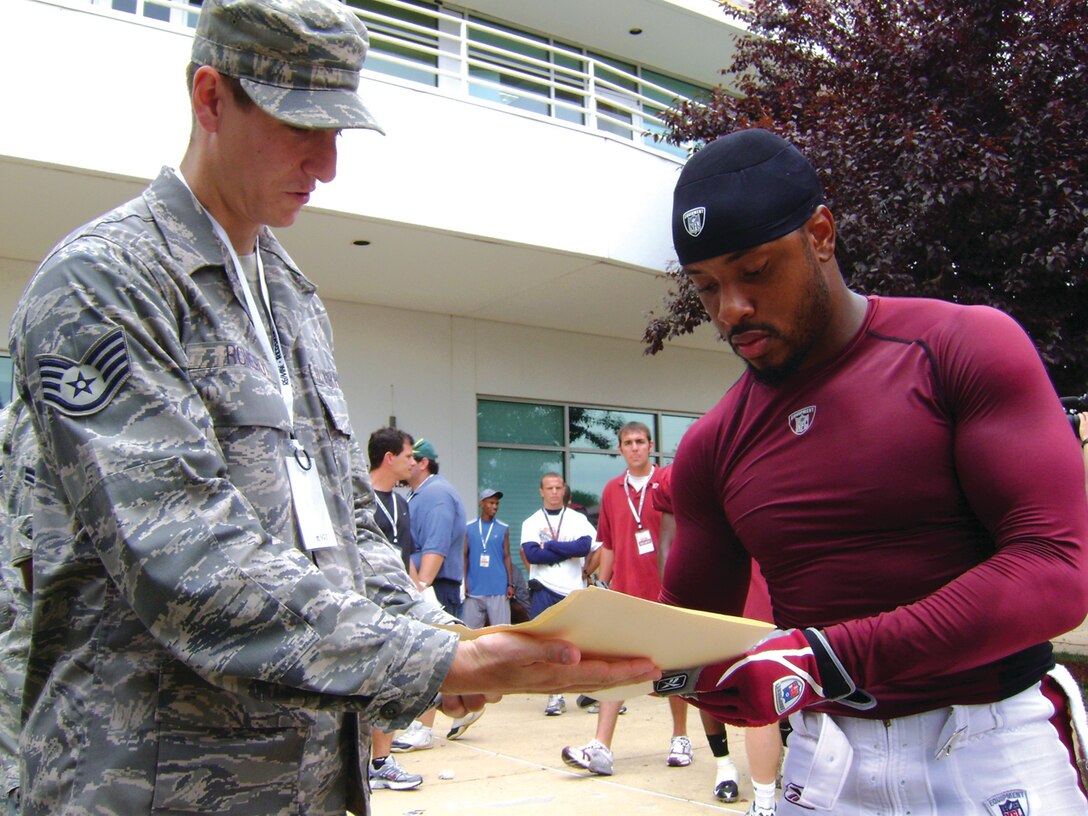 Santana Moss, Washington Redskins wide receiver, signs an autograph for Staff Sgt. Brandon Romero, 89th Communications Squadron, July 23. A group of Andrews Airmen were invited to Redskins Park in Loudon County, Va., to watch the team practice for the 2008-2009 season. The Airmen were also given a tour of the Redskins training facility.