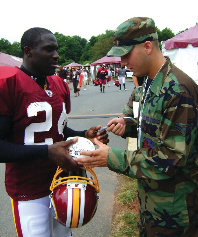 Shawn Springs, Washington Redskins cornerback, signs an autograph for Airman 1st Class Danna Justis, 79th Medical Support Squadron, July 23. A group of Andrews Airmen were invited to Redskins Park in Loudon County, Va., to watch the team practice for the 2008-2009 season. The Airmen were also given a tour of the Redskins training facility.