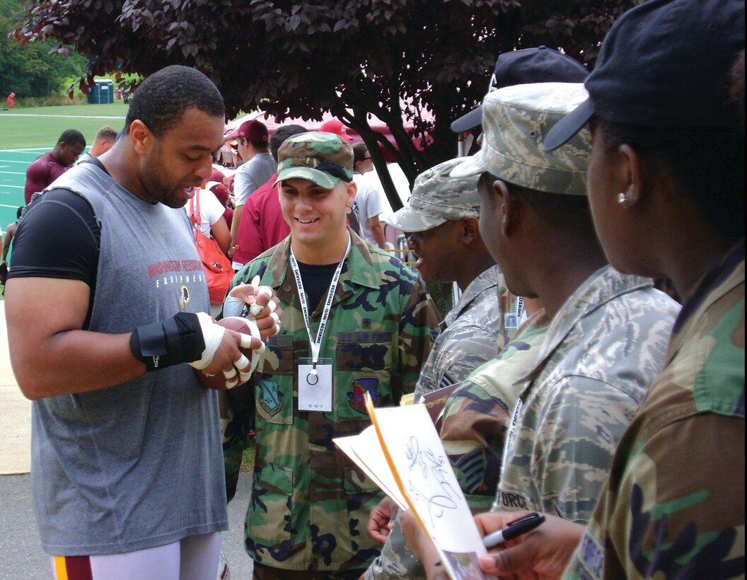 Demetric Evans, Washington Redskins defensive end, signs autographs for a group of Andrews Airmen who were invited to Redskins Park in Loudon County, Va., to watch the team practice for the 2008-2009 season. The Airmen were also given a tour of the Redskins training facility.