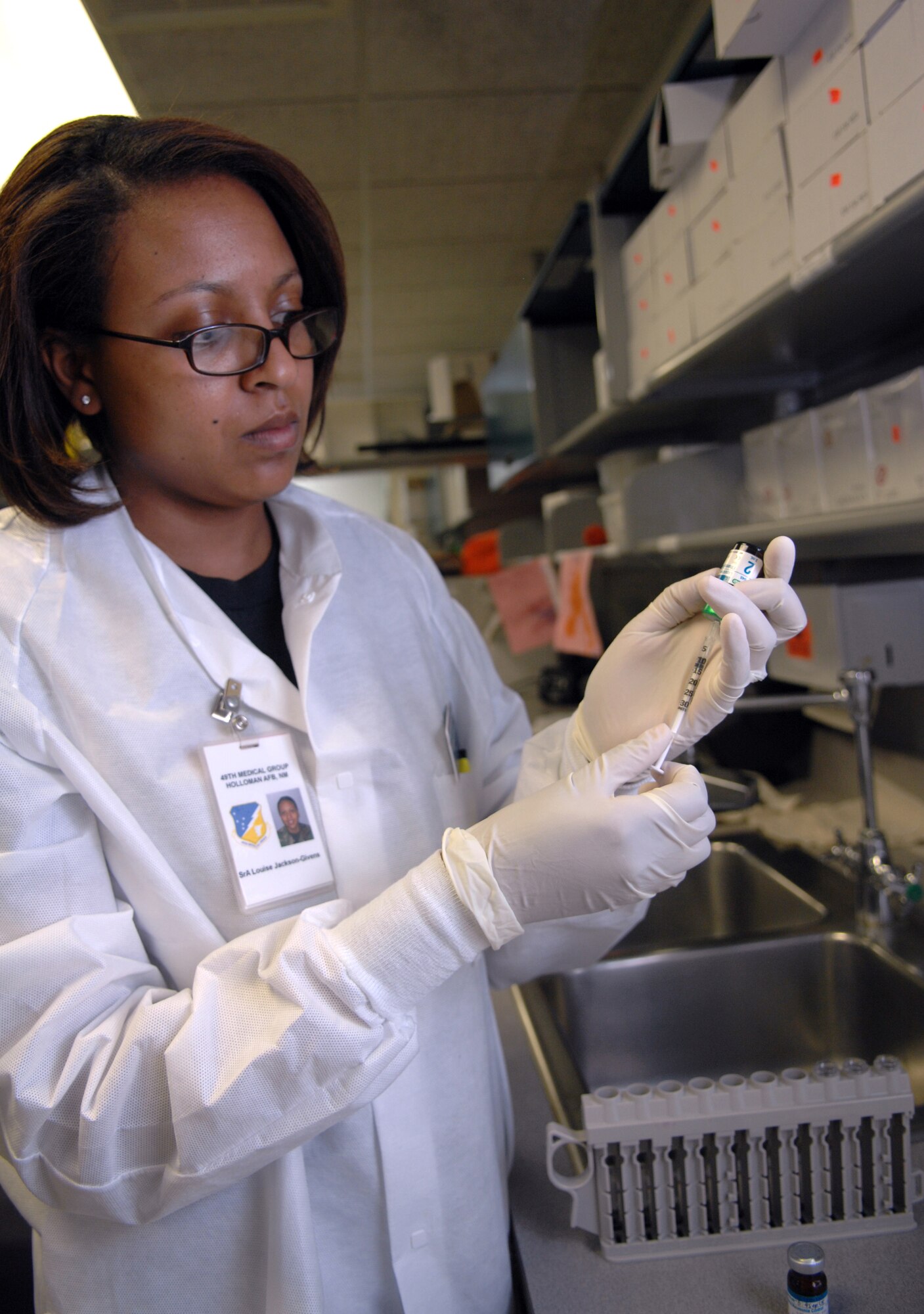 Senior Airman Louise Jackson-Givens, 49th Medical Support Squadron, uses a needle to extract serrum to be used in a College of American Pathology (CAP) survery in the laboratory at the 49th Medical Group Clinic at Holloman Air Force Base, N.M., August 14. A CAP survey is used to test the Vitros 250 machine, which is used to test serrums. The survey is done by placing different pooled serrums into test tubes and inserting it into the machine. They then check the results and make sure they are correct. A CAP survey is done two to three times a month. (U.S. Air Force photo/Airman Sondra M. Wieseler)