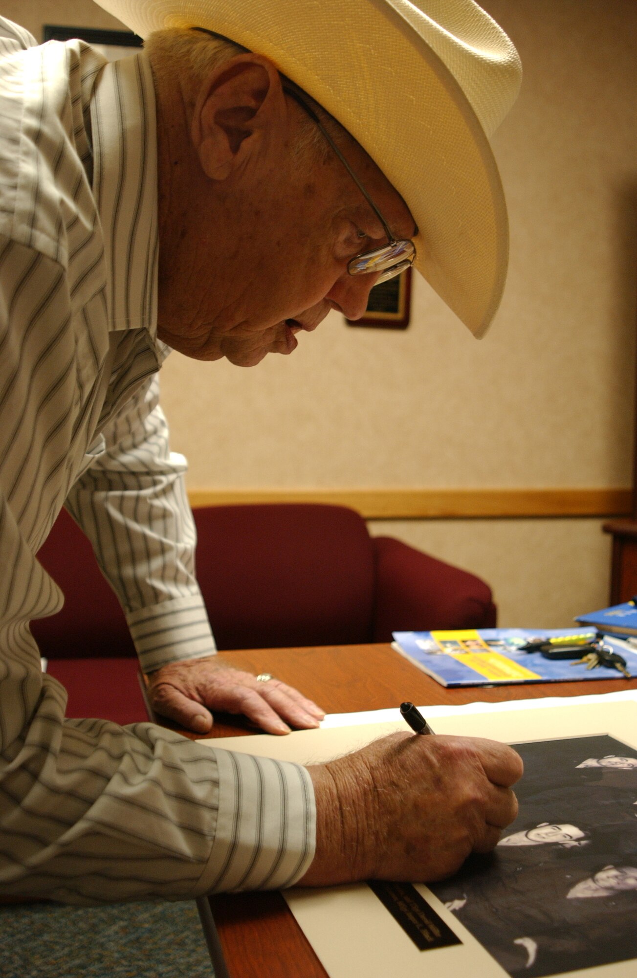 Retired Chief Master Sgt. Truman Woodford signs a photo Aug. 20 of the original group of Airmen hand-picked to install Vance’s first and only altitude chamber. (U.S. Air Force photo by Staff Sgt. Brian Hill)
