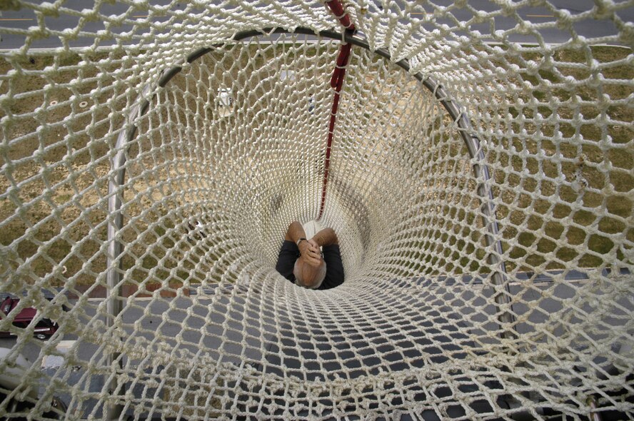 DOVER AIR FORCE BASE, Del. – Ralph Baker, inventor of the Baker Life Chute, demonstrates the correct way to slide down the chute during egress training at Dover’s Air Traffic Control Tower Aug. 15. The chute is 13 feet in diameter, 112-feet long and is made with 66 strands of rope. The chute is used to quickly and safely evacuate Airmen from the six-story tower. Airmen must keep their bodies straight and their hands above their heads to safely take the plunge. Airmen can also control the speed of their descent with their legs. (U.S. Air Force photo/Airman 1st Class Shen-Chia Chu) 