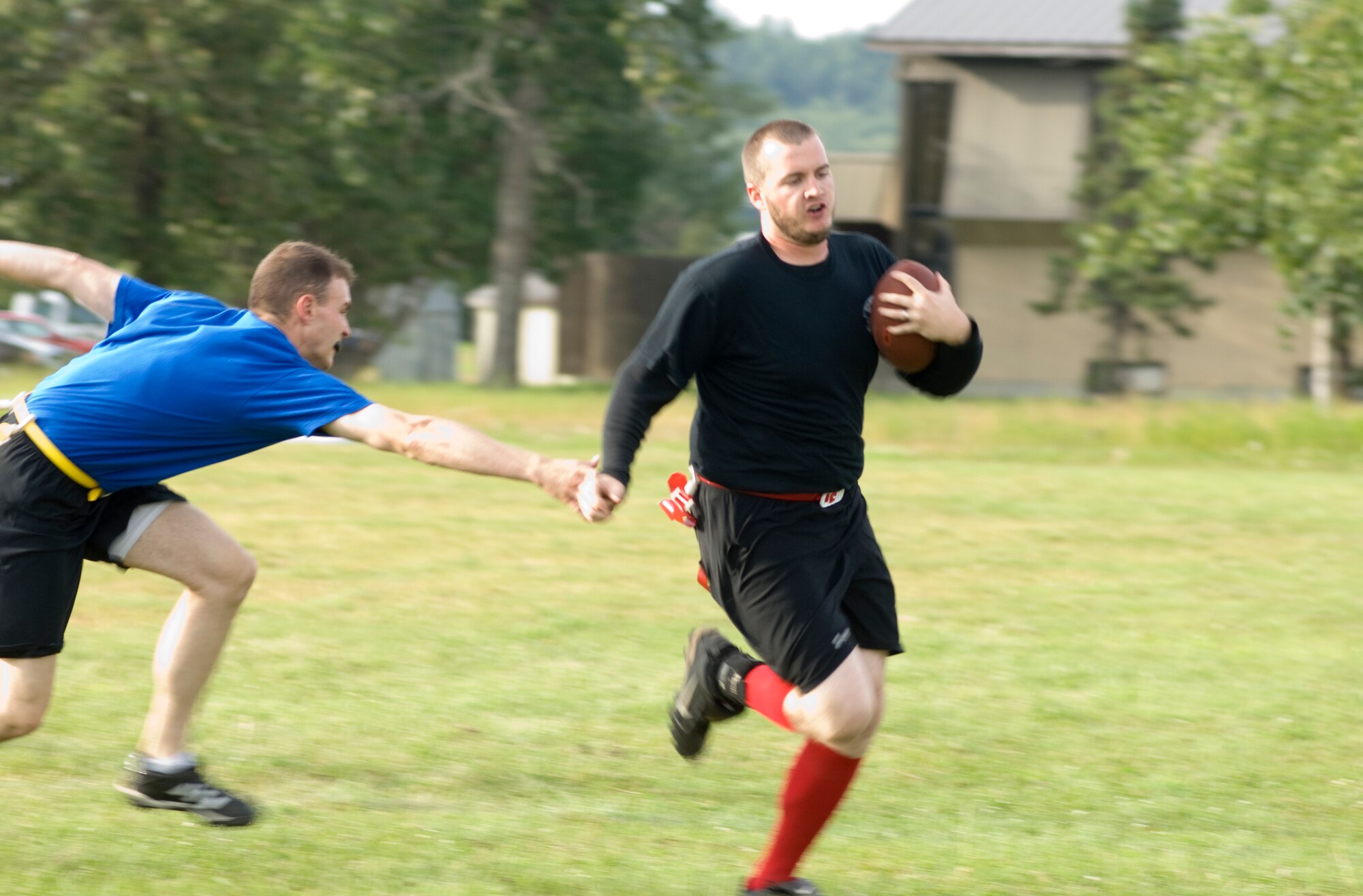 ELMENDORF AIR FORCE BASE, Alaska -- Adam Crow, a member of the 381st Intelligence Squadron, attempts to run away from John Clements during the flag football game Aug. 19. Scoring the first touchdown of the contest, the team fell short, 19-7. (U.S. Air Force photo)