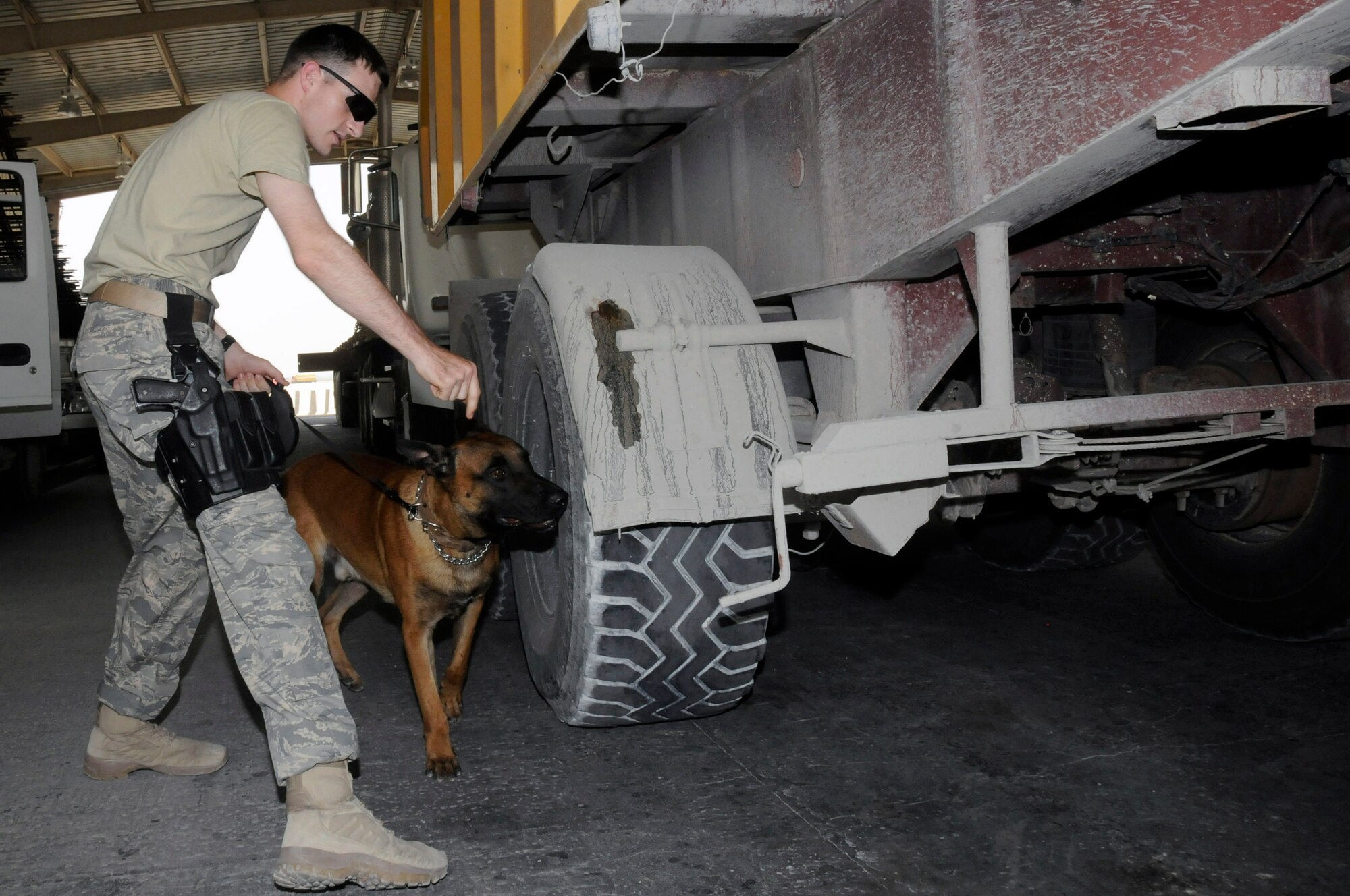 Staff Sgt. Logan Ray and Lennox check a truck Aug. 19 waiting to enter an air base in Southwest Asia. Sergeant Ray, a military working dog handler assigned to the 379th Expeditionary Security Forces Squadron, and the rest of his team ensure the safety and security of the air base by carefully inspecting all incoming vehicles for explosives and weapons. Sergeant Ray, a native of Hyattsville, Md., is deployed from Andrews Air Force Base, Md.  (U.S. Air Force photo/Staff Sgt. Darnell T. Cannady)