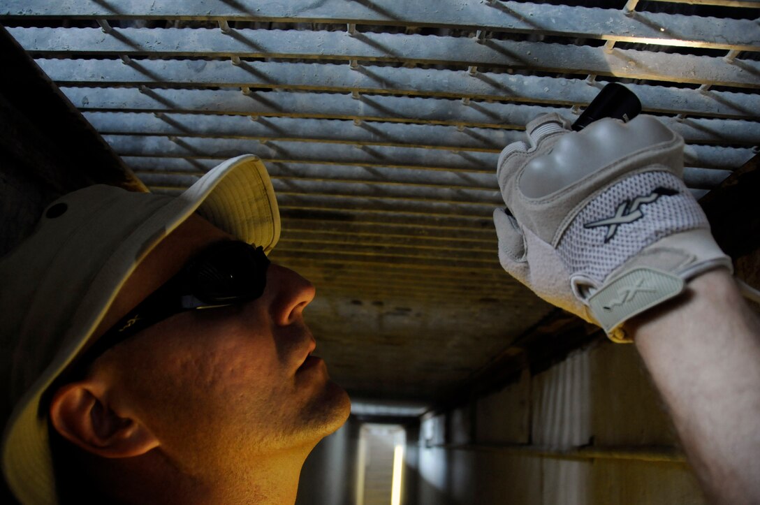 Staff Sgt. Darryl Gullekson, a search member assigned to the 379th Expeditionary Security Forces Squadron, stands in a search pit to inspect the undercarriage of a vehicle Aug. 19 at an air base in Southwest Asia.  Sergeant Gullekson and the rest of his team ensure the safety and security of the air base by carefully inspecting all incoming vehicles for explosives and weapons.  Sergeant Gullekson, a native of Muskego, Wis., is deployed from Scott Air Force Base, Ill.  (U.S. Air Force photo/Staff Sgt. Darnell T. Cannady)