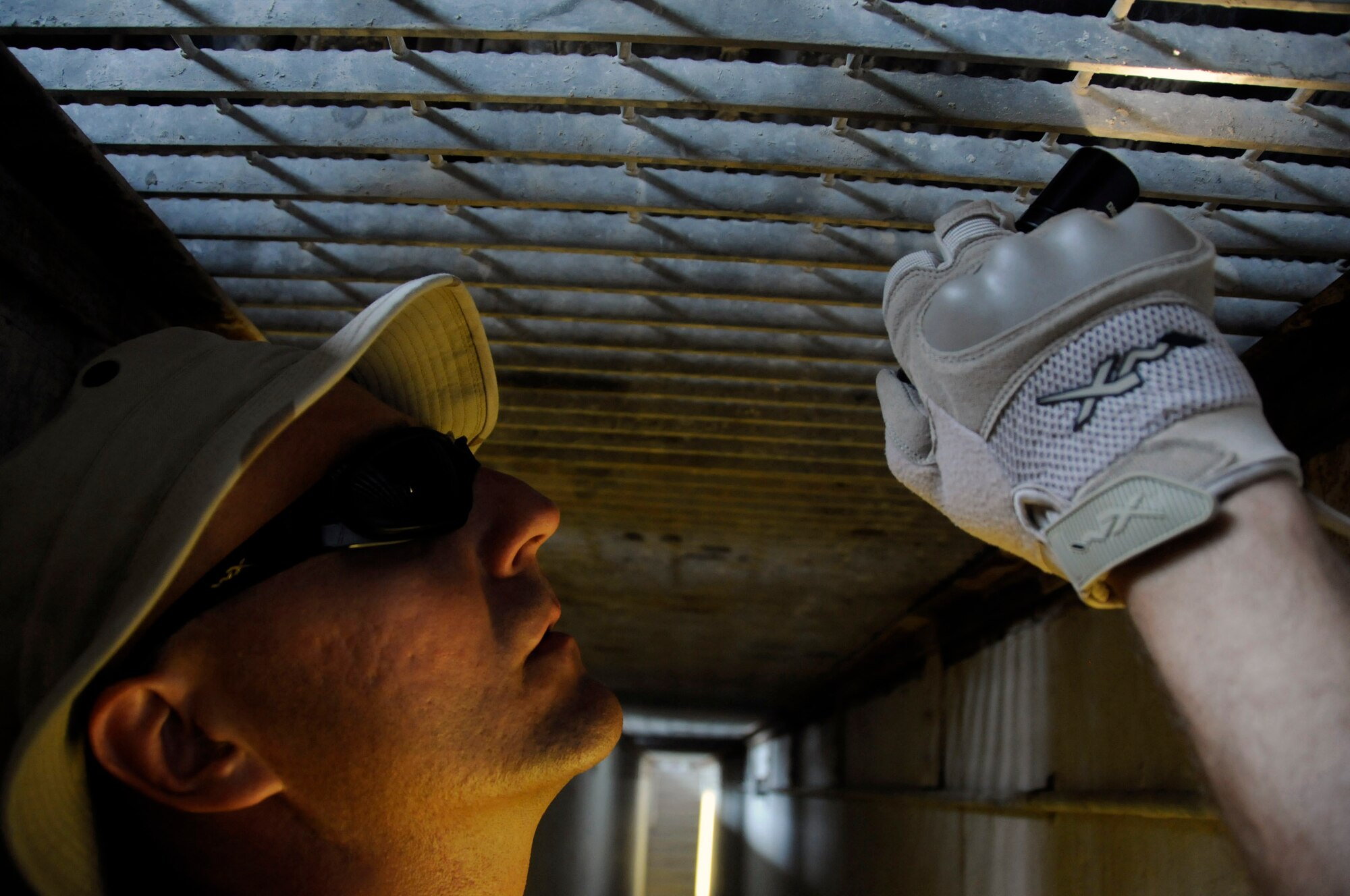 Staff Sgt. Darryl Gullekson, a search member assigned to the 379th Expeditionary Security Forces Squadron, stands in a search pit to inspect the undercarriage of a vehicle Aug. 19 at an air base in Southwest Asia.  Sergeant Gullekson and the rest of his team ensure the safety and security of the air base by carefully inspecting all incoming vehicles for explosives and weapons.  Sergeant Gullekson, a native of Muskego, Wis., is deployed from Scott Air Force Base, Ill.  (U.S. Air Force photo/Staff Sgt. Darnell T. Cannady)