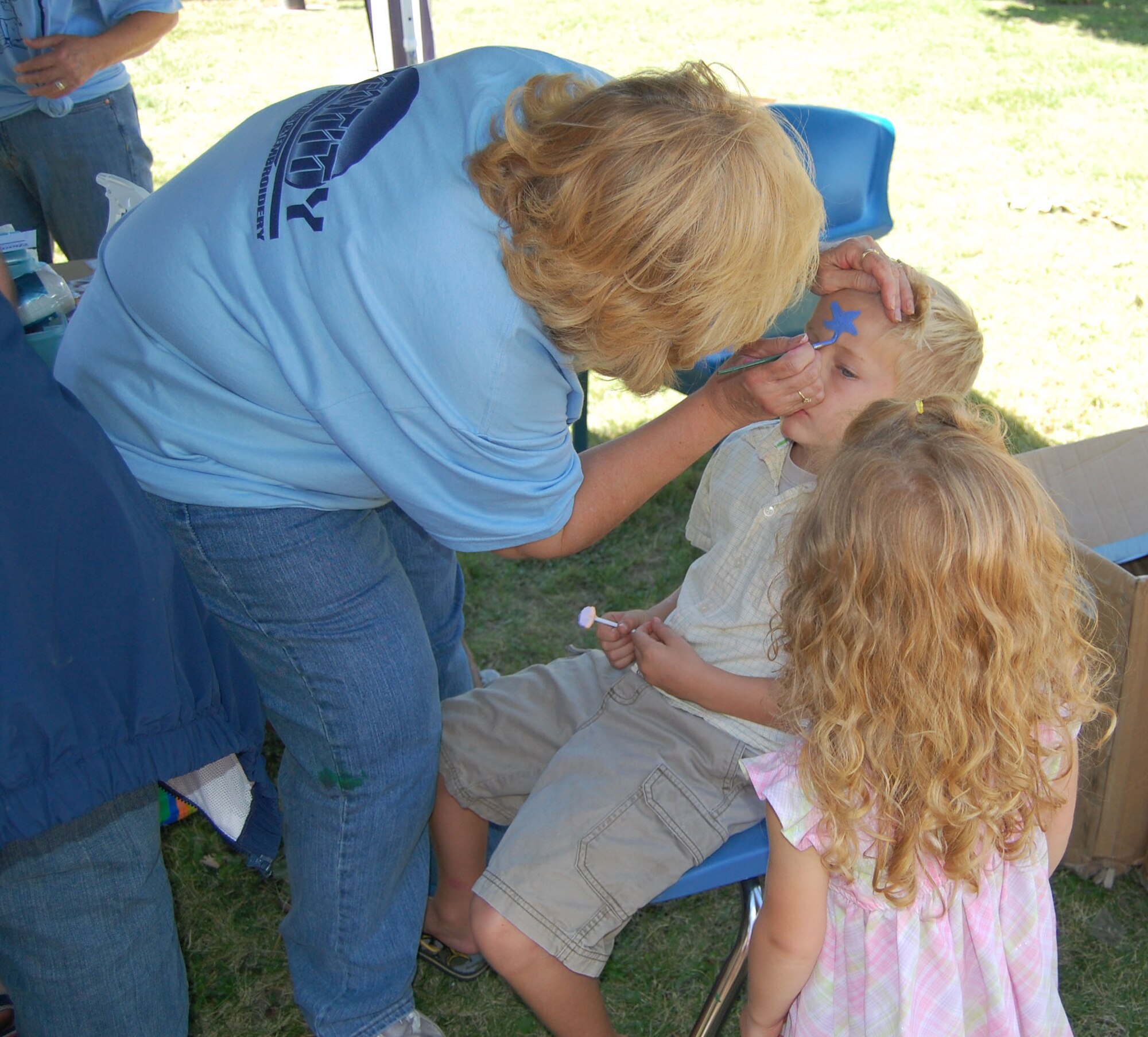 Little Warrior Ryan, 6, gets his face painted by volunteer Peggy Vaccaro, while his friend Chloe, 3, admires the work. Several thousand people filled Sun Plaza Park at Malmstrom Air Force Base Aug. 15 for the wing’s annual summer picnic. Servicemembers and their families enjoyed free food, music, games, a car show, giveaways, bouncy castles and much more. (U.S. Air Force photo/Senior Airman Eydie Sakura).