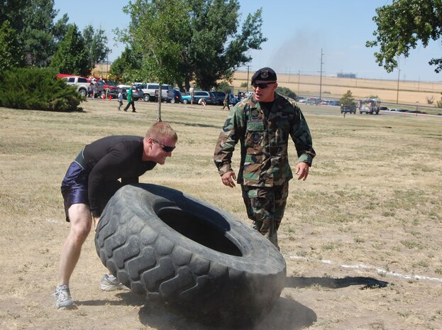 Senior Airman Samuel Fullerton participates in the Grizzly Challenge Competition’s tire flip while fellow 341st Security Forces Group tactical response force team member, Senior Airman Jeromy Thatcher, cheers him on at the base picnic Aug. 15. Several thousand people filled Sun Plaza Park at Malmstrom Air Force Base for the wing’s annual summer picnic. Servicemembers and their families enjoyed free food, music, games, a car show, giveaways, bouncy castles and much more.  (U.S. Air Force photo/Senior Airman Eydie Sakura).