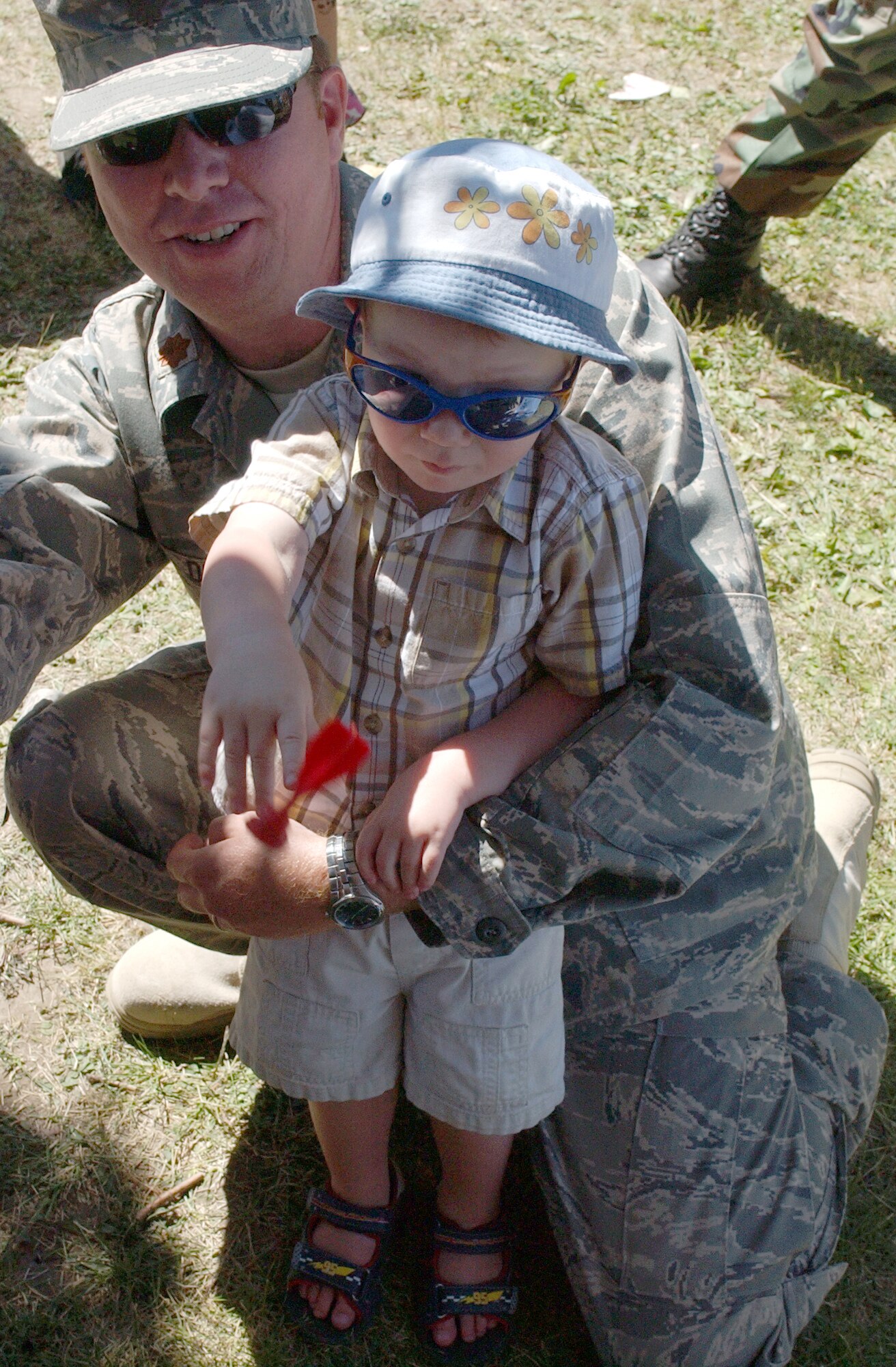 Maj. James Duke holds his son, John, 2, as the younger Duke throws a Velcro dart at a target during the Malmstrom Air Force Base picnic Aug. 15.  Major Duke is the operations flight commander in the 341st Civil Engineer Squadron. (U.S. Air Force photo/Maj. David Kurle)