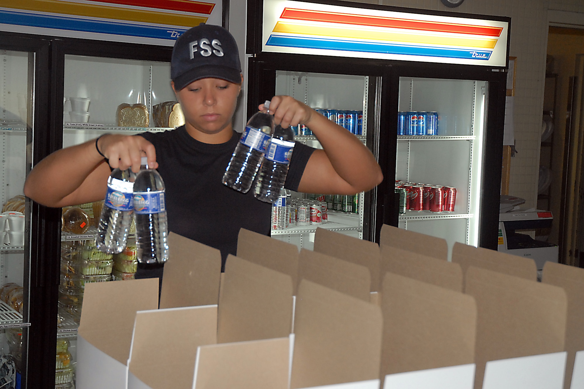 Airman 1st Class Nicolette Newton places water bottles in box lunches at the 437th Force Support Squadron Flight Kitchen Aug. 20. The flight kitchen routinely prepares up to 200 box lunches daily for aircrew and flightline workers. Airman Newton is a food services journeyman with the 437 FSS. (U.S. Air Force photo/Airman 1st Class Melissa White)