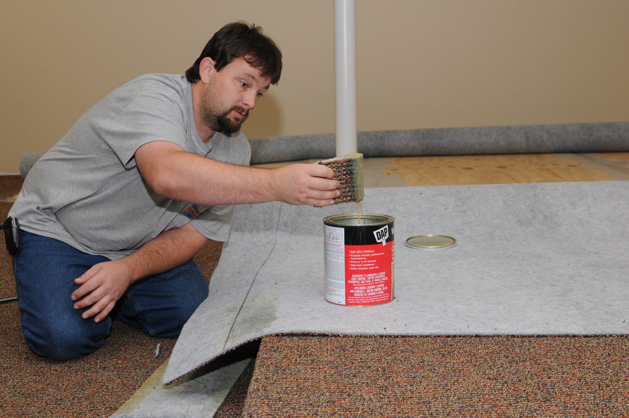 Carpet installer Brian Dison puts new flooring in place in the temporary activities center being created in a former dining area in Locker House.  (U.S. Air Force photo by Kemberly Groue)