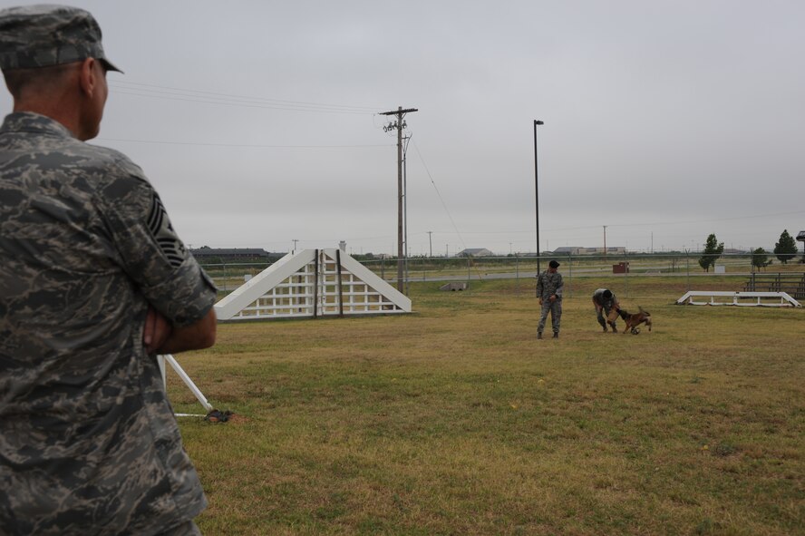 DYESS AIR FORCE BASE, Texas-- Command Chief Master Sgt. Stephen Sullens, Air Combat Command, command chief, watches as the K-9 team demonstrate attack commands at the kennels here, Aug. 15. The K-9 team performed a 15-minute demostration and guided a dog through the obstacle course.  (U.S. Air Force photo/ Senior Airman Courtney Richardson)