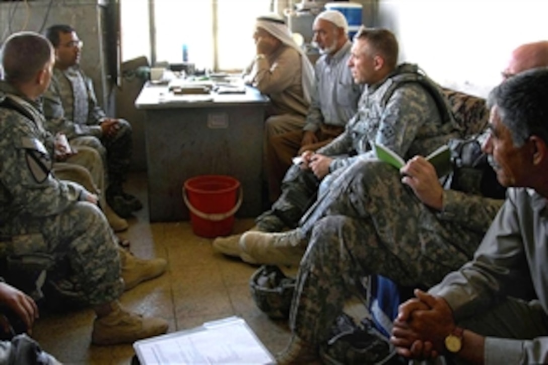 U.S. Army Capt. John Rasmussen, left, and Lt. Col. Eric Johnson, right, and an interpreter, rear left, discuss economics with local shop owners at a steel supply industrial park in East Al Sinaa, Mosul, Iraq, Aug. 17, 2008. Rasmussen is assigned to Company D, 1st Battaltion, 8th Infantry Regiment; Johnson is assigned to 3rd Armored Cavalry Regiment.