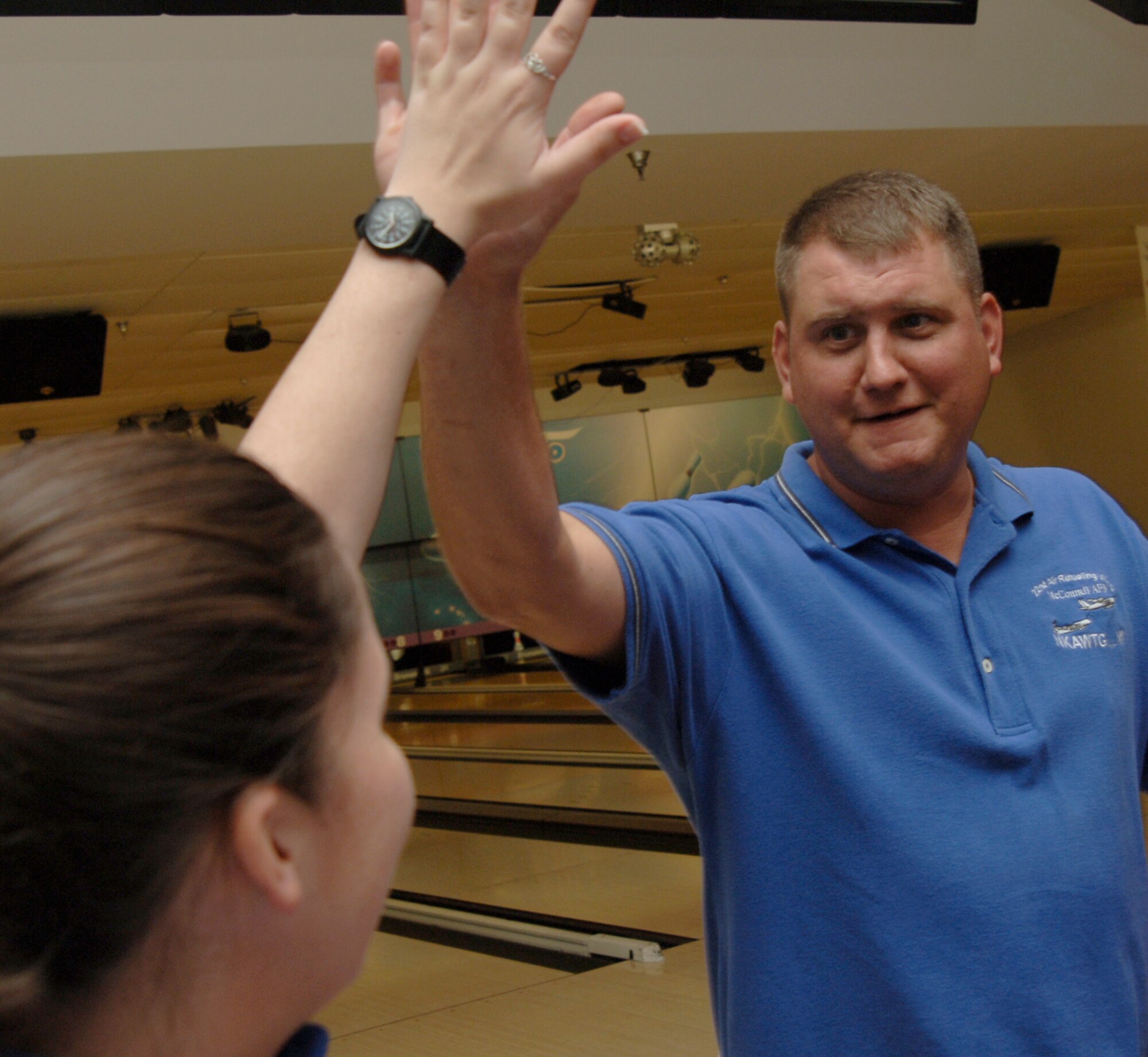 MCCONNELL AIR FORCE BASE, Kan. -- Tech. Sgt. Shad Winters high fives 1st Lt. Moira Tracey, both from the 22nd Air Refueling Wing protocol office, during the Air Force Ball Bowling Fundraiser at the Robert J. Dole Community Center, Aug. 15. (Photo by Senior Airman Roy Lynch III)