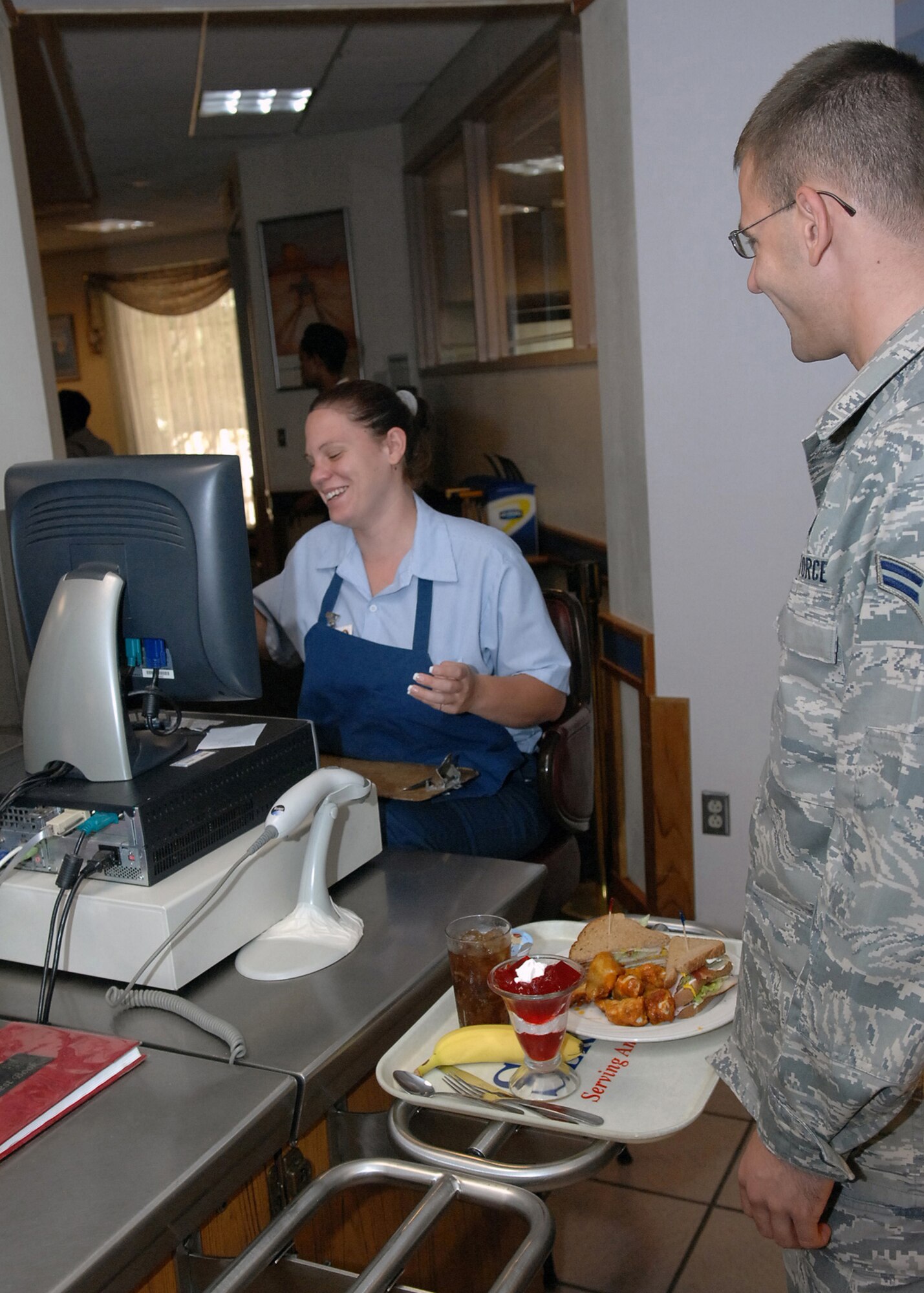 CANNON AIR FORCE BASE, N.M. -- Michelle Mayes, 27th Special Operations Services Squadron, rings up lunch for Airman 1st Class Michael Huggins, 27th Special Operations Civil Engineer Squadron. Pecos Trail Dining Facility provides breakfast, lunch and dinner for Airmen at Cannon. (U.S. Air Force photo/Airman 1st Class Danielle Martin)