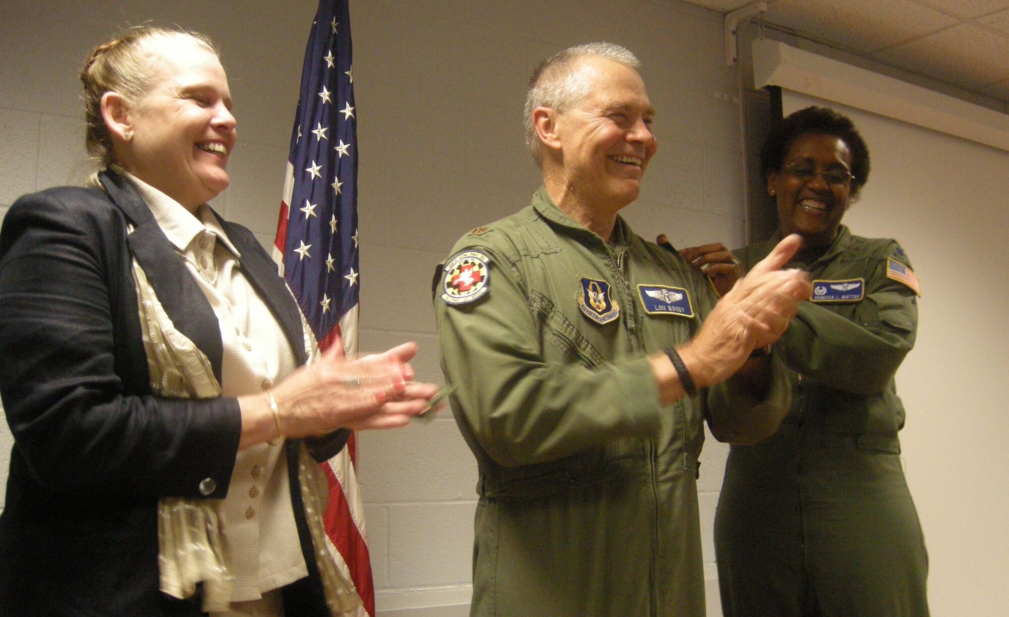 ANDREWS AIR FORCE BASE, Md. -- Lt. Col. Louie Woody, 459th Aeromedical Evacuation Squadron flight nurse, gets his new rank pinned on by spouse (left) Col. Kathleen Woody and Lt. Col. Vanessa Mattox, 459th AES commander, here Aug. 20. Colonel Woody's new rank is the result of a very rare accelerated promotion that requires a member to be in a position commensurate with the rank to which they are promoted. The member's commander requests permission for the member to pin on the rank at a date earlier than the selection board has assigned the member. In this case, the 64-year-old prior enlisted Colonel Woody pinned on many months before he expected to. (U.S. Air Force photo/Tech. Sgt. Amaani Lyle)