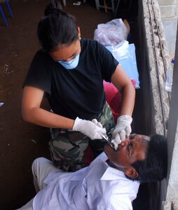 CLUBKI, Honduras - Dr. Alba Rivera, Honduran Army, takes out a man's tooth in a medical readiness exercise here Aug. 19. Dr. Rivera is part of a multi-national team training in an exercise to prepare for a disaster. Countries in the exercise include Honduras, Guatemala, El Salvador, and the United States. (U.S. Air Force photo by Staff Sgt. Joel Mease)