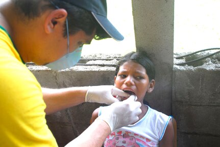CLUBKI, Honduras - Dr. Juan Alejandro Burgos pulls a tooth from a young child Aug. 19 in a medical readiness exercise here. Dr. Burgos is part of a multi-national team that came to the La Mosquita region to train for a medical disaster and help the people in these villages. (U.S. Air Force photo by Staff Sgt. Joel Mease)