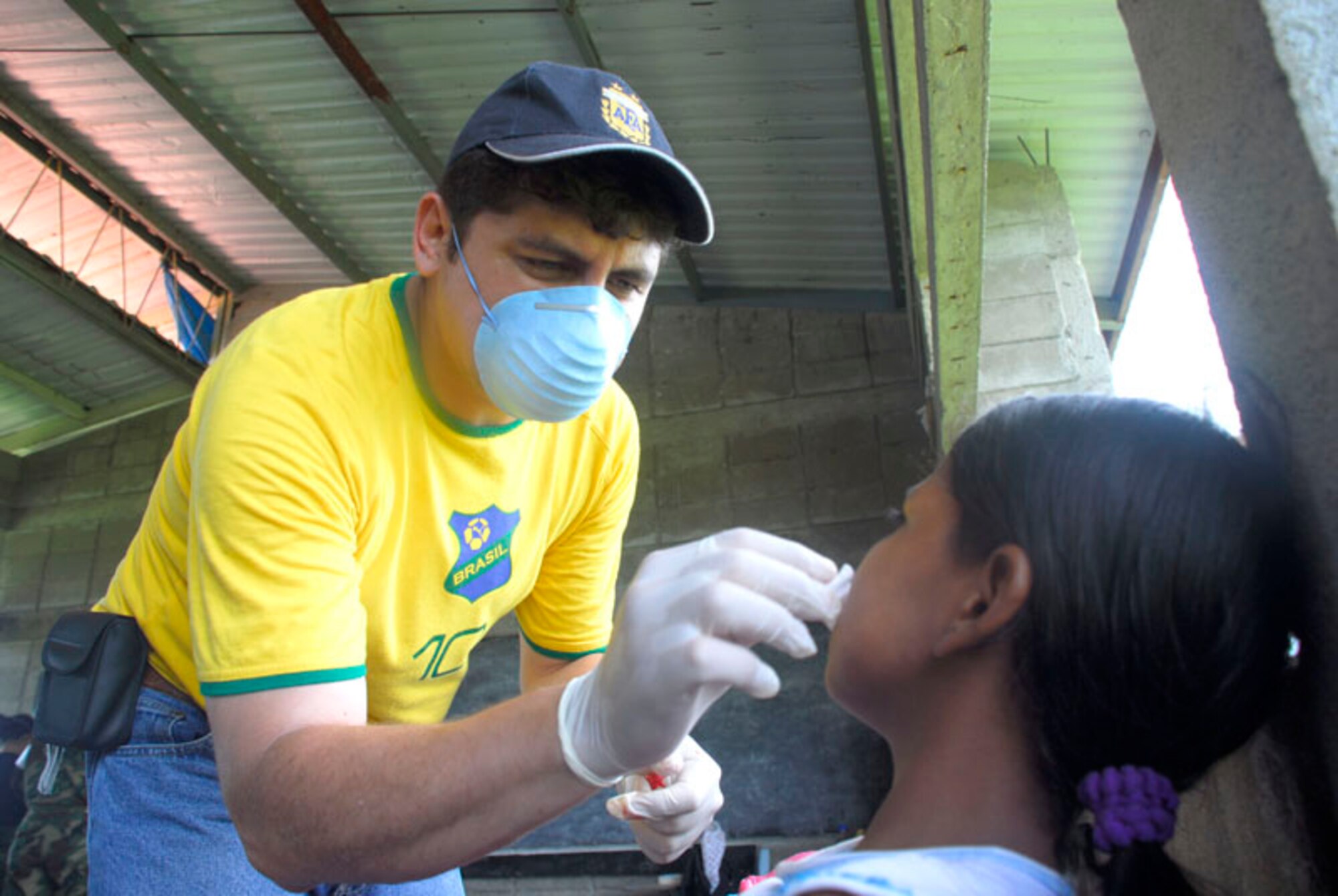CLUBKI, Honduras - Dr. Juan Alejandro Burgos pulls a tooth from a young child Aug. 19 in a medical readiness exercise here. Dr. Burgos is part of a multi-national team that came to the La Mosquita region to train for a medical disaster and help the people in these villages. (U.S. Air Force photo by Staff Sgt. Joel Mease)