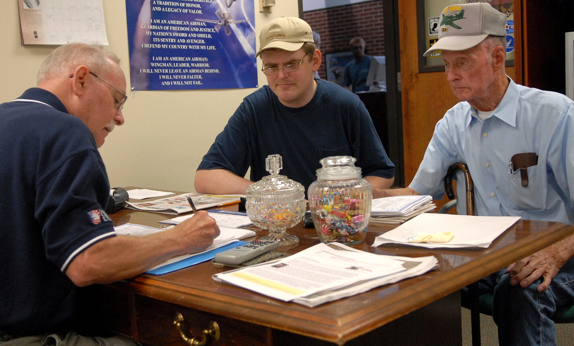 Retired Senior Master Sgt. Joe Wheeler, Little Rock Air Force Base Retiree Activities Office assistant, reviews documents with Damon Poole II, center, and retired Air Force Master Sgt. Damon Poole, right.(U.S. Air Force photo by Senior Airman Chris Willis)
