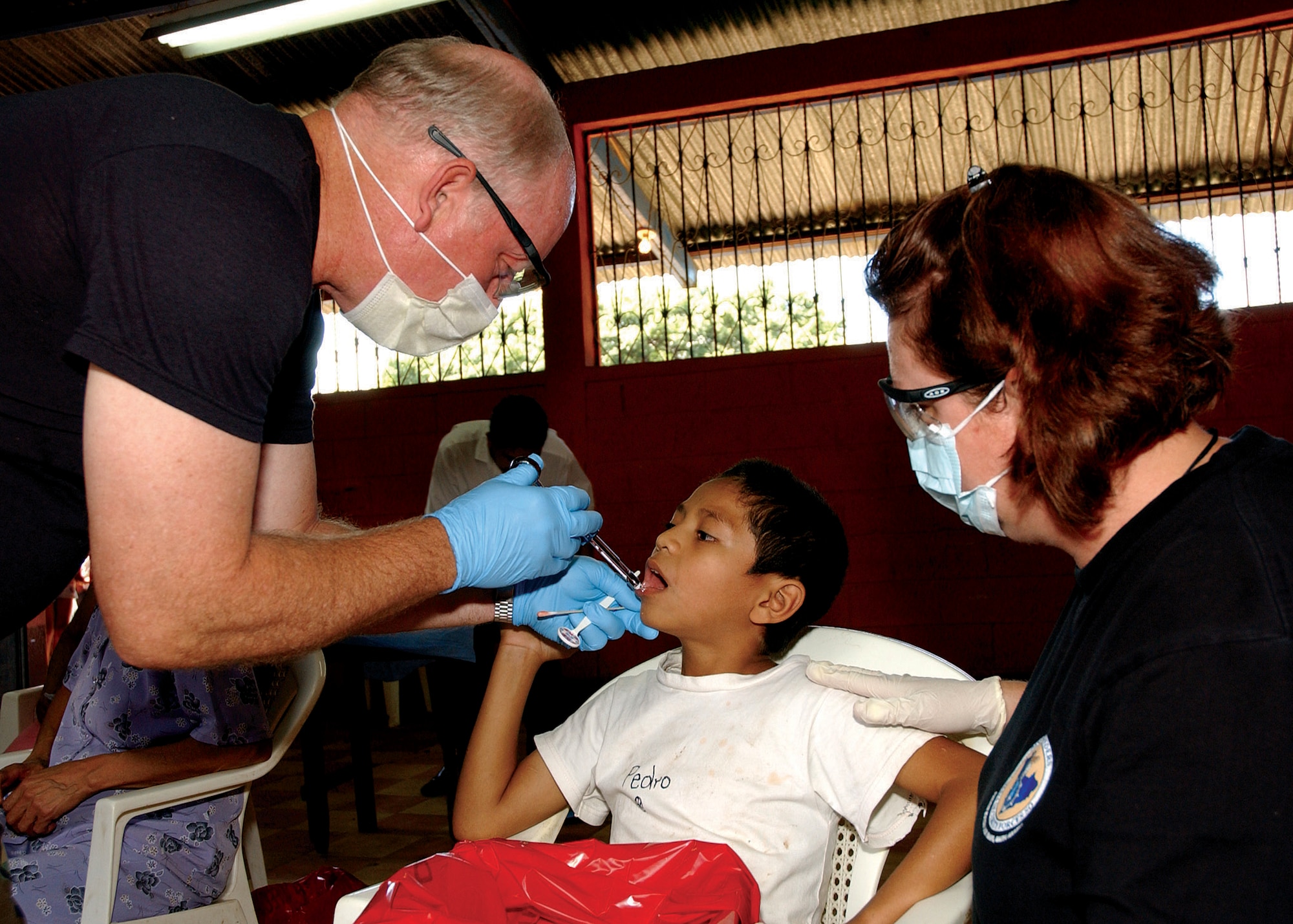 Lt. Col. (Dr.) Philip Bales gives 8-year-old Pedro Mayen an injection before extracting a tooth while Tech. Sgt. Rose Hartzell comforts the boy Aug. 18 in Santa Rosa Guatemala. Colonel Bales is assigned to the 173d Medical Group of the Oregon National Guard, and Sergeant Hartzell is a 163rd Medical Group dental technician from the California Air National Guard. (U.S. Air Force photo/Capt. Al Bosco) 

