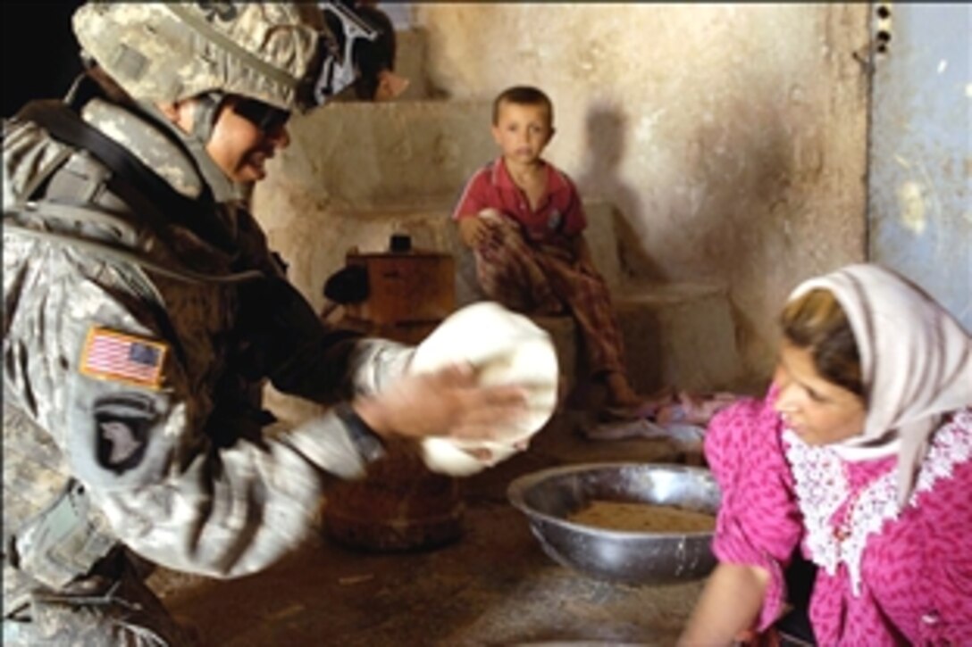 An Iraqi woman teaches a U.S. Army soldier how to bake flatbread in the village of Jakara, Iraq, Aug. 16, 2008. 
