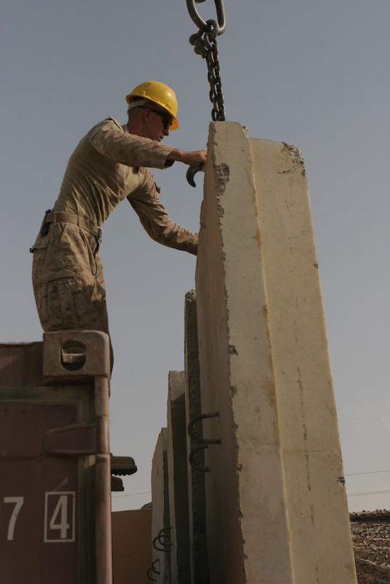 RAMADI, Iraq (August 21, 2008) – Lance Cpl. Steven T. Wise, a heavy equipment operator with Combat Logistics Company 111, Combat Logistics Battalion 1, 1st Marine Logistics Group helps guide a T-wall into place at the Ramadi Government Center on Aug. 21. The HE operators installed concrete walls throughout the compound to add additional protection for Coalition Forces and civilians who work there. “The T-walls we are installing today will block the view of buildings that surround the Government Center in the case of an enemy sniper,” said Cpl. Chris R. Yohe, HE operator with CLC-111. “The barriers hide the main walkways that are constantly being used within the center.” (Photo by Lance Cpl. Jacob A. Singsank)