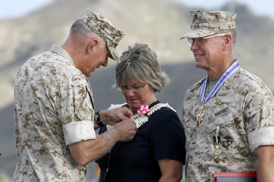 Gen. James T. Conway, (left) Commandant of the Marine Corps, presents Gayle Goodman, wife of Lt. Gen. John F. Goodman, (right) commander, U.S. Marine Corps Forces, Pacific, with a Superior Public Service Award during her husband's change of command and retirement ceremony on the flightline here Aug 22.