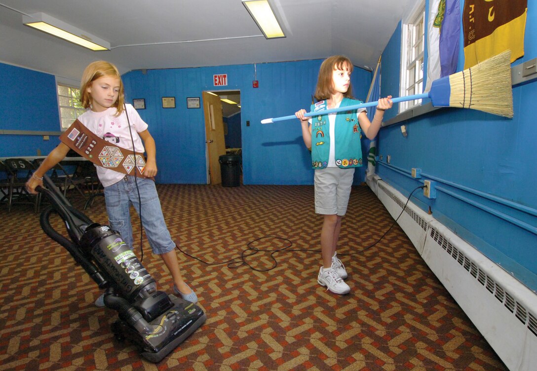 Andrews Girl Scouts Paige Brewer, 8, left, and Kaitlyn White, 9, clean in unison at their Girl Scout house recently. They joined the entire Girl Scout troop spending approximately four hours on the self help cleanup project, which included old furniture disposal, sweeping cobbwebs and vacuuming. (U.S. Air Force photo by Bobby Jones)