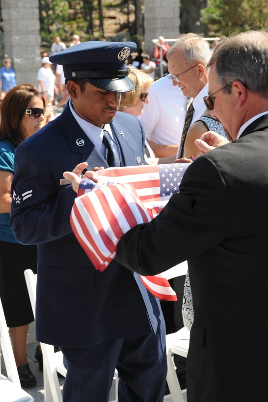 Airman 1st Class Tarun John, 28th Civil Engineer Squadron pest management journeyman, receives an American flag during a naturalization ceremony at Mount Rushmore National Memorial, S.D., Aug. 21. Five Airmen from Ellsworth took their last step to become citizens of the United States.  (U.S. Air Force photo /Airman 1st Class Adam Grant) 