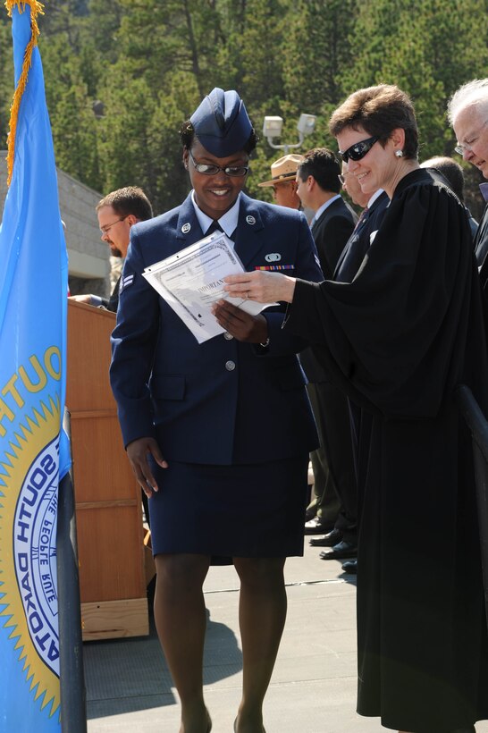 Airman 1st Class Sanaka Patrick, Air Force Financial Services Center temporary duty technician, walks off stage after receiving her certificate of citizenship during a naturalization ceremony at Mount Rushmore National Memorial, S.D., Aug. 21. Airman Patrick is one of the five Airmen from Ellsworth who took her last step to become a citizen of the United States. (U.S. Air Force photo /Airman 1st Class Adam Grant) 