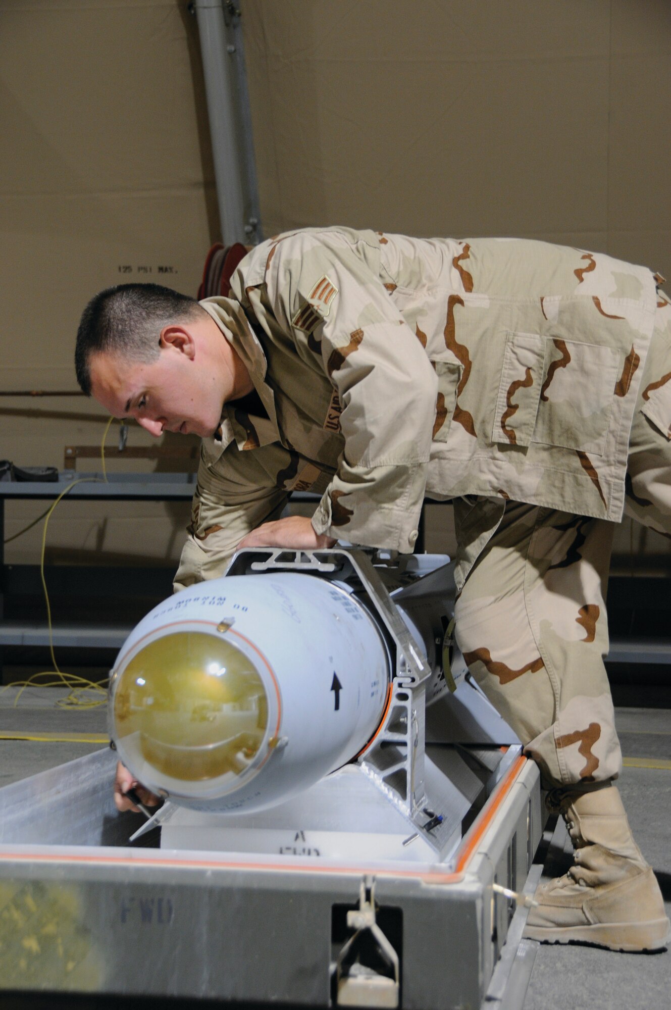 Senior Airman Fernando Mora, 379th Expeditionary Maintenance Squadron, pulls the pin on a harness holding an AGM 65 Missile here Aug. 19. Airman Mora removed the harness as one of the steps in a visual inspection of the missile.  Airman Mora hails from San Diego, Calif., and is deployed from Nellis Air Force Base, Nev. (U.S. Air Force photo by Tech. Sgt. Michael Boquette)