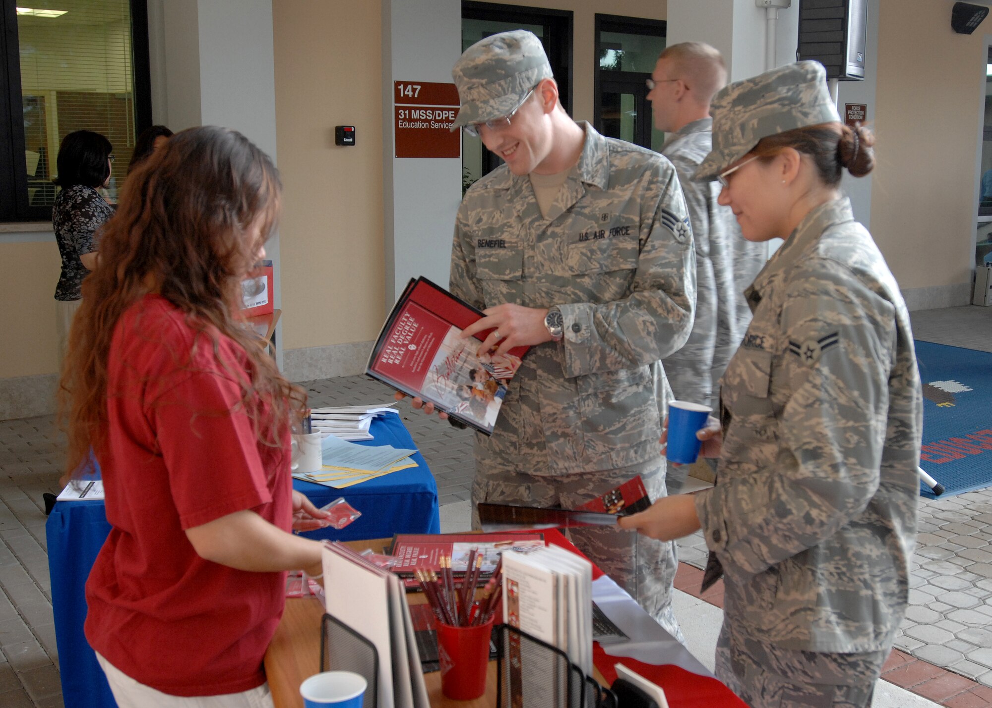 AVIANO AIR BASE, Italy -- Amber Sweeney helps Senior Airman Robert Benefiel and Airman 1st Class Alexandra Benefiel learn more about the University of Maryland University College (OU), Aug. 8 at the Aviano Education Center. OU offers many classes on-site, on-line and through independent study, to help Airmen achieve a Master of Arts in International Relations.    (U.S. Air Force photo/Airman 1st Class Tabitha M. Mans)