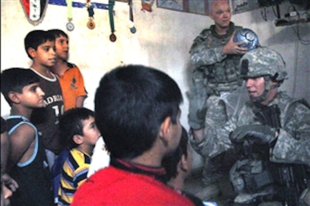 U.S. Army Sgt. Michael Horst explains to Iraqi orphans that they must share five donated soccer balls as Sgt. Kevin Dodson displays a ball at the orphanage in the Sadr City district of Baghdad, Iraq, Aug. 18, 2008. Horst is assigned to the 432nd Civil Affairs Battalion; Dodson is assigned to the 4th Infantry Division.  