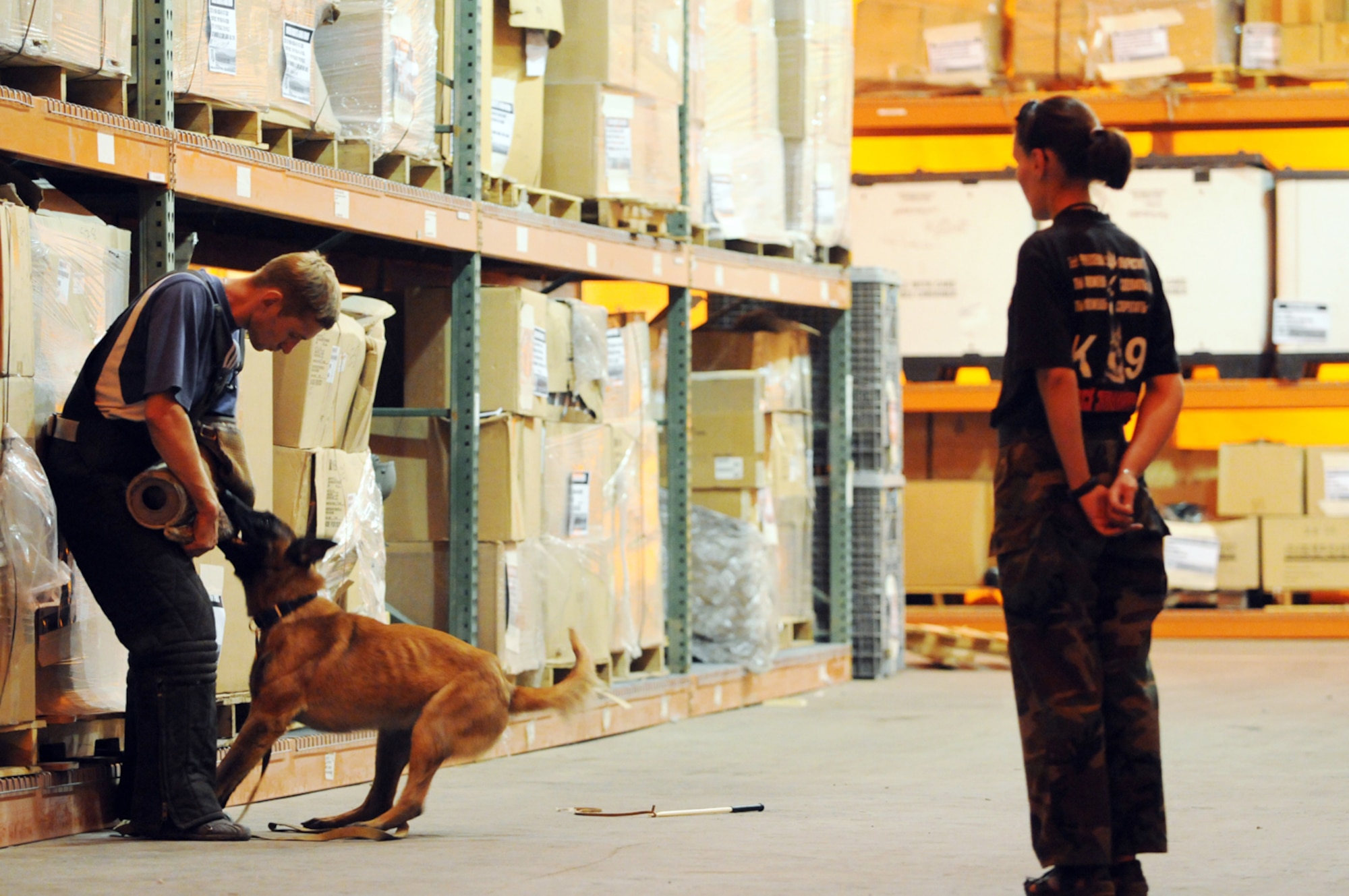 MANAS AIR BASE, KYRGYZ REPUBLIC--Konstantin Ilyenko and Sgt. Svetlana Kuzhetsova, both Kyrgyz dog handlers from the Kyrgyz State Security Service, train an explosive detection and security dog to seek out suspicious items in a warehouse at Manas AB, Aug. 19. K-9 security dog handlers from the base's 376th Expeditionary Security Forces Squadron train weekly with their Kyrgyz counterparts from the nearby Kyrgyz Republic Capital of Bishkek. The training offers the opportunity to exchange ideas and techniques between the two. (Air Force photo / Airman 1st Class Ruth Holcomb) 