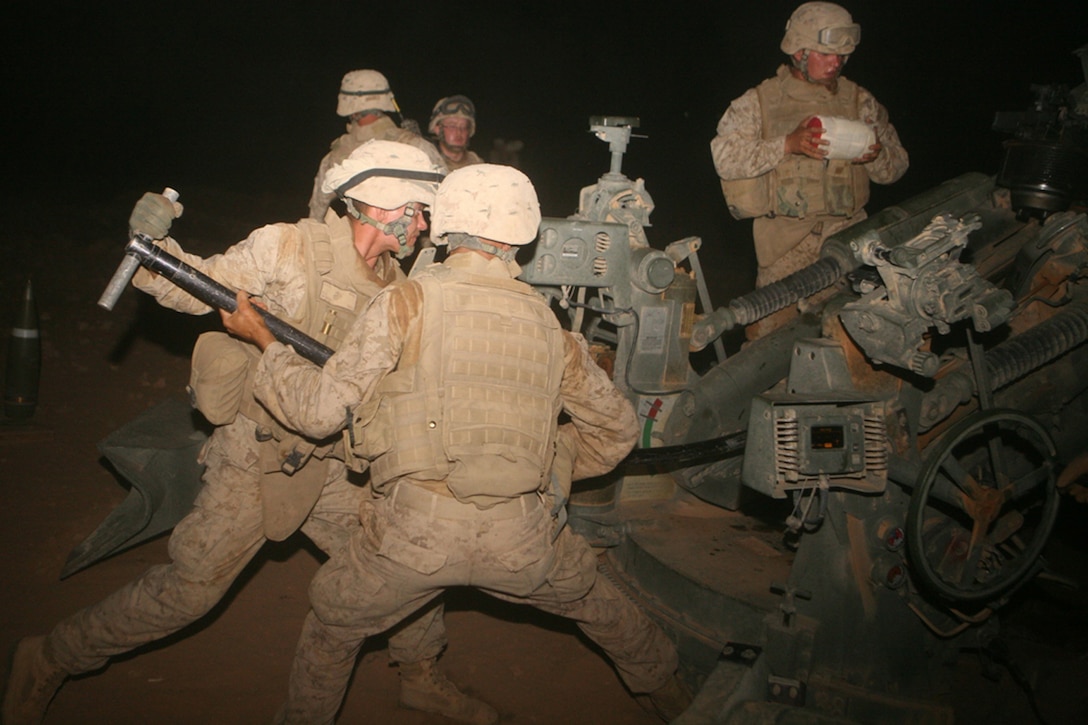 Injecting an illumination round into the chamber of a M-777 Howitzer, Lance Cpls. Justin R. Burch (left), and Kristopher A. Bowers, both cannoneers with Mike Battery, 3rd Battalion, 14th Marine Regiment, 2nd Light Armored Reconnaissance Battalion, Regimental Combat Team 5, ensure the round is properly inserted during an illumination round shoot at Patrol Base El Dorado, Iraq, Aug. 23. When not illuminating the night sky, the battery has engaged in combat patrols through the city  of Rutbah. Mike Battery is a reserve artillery battery based out of Chattanooga, Tenn., and attached to 2nd LAR Bn.::r::::n::