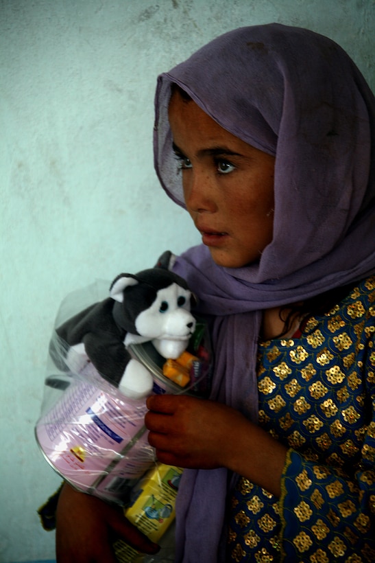 An Afghan girl gathers the toys, cereals and medications she received following a visit to a Medical Capabilities (MEDCAP) health cooperative held Aug. 24 in Delaram, Afghanistan.  Service members of Task Force 2d Battalion, 7th Marine Regiment, 1st Marine Division, Combined Joint Task Force Phoenix, provided medical and dental exams to more than 180 Afghan patients during the MEDCAP. (U.S. Marine Corps photo by Cpl. Steve Cushman)